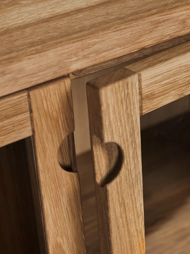 Dos paneles de madera clara, cada uno con un recorte en forma de corazón, en un mueble.