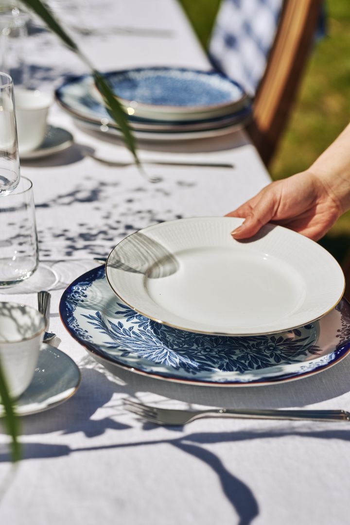Una mesa tradicional de midsummer en azul y blanco con el plato sueco Grace Gala con contorno dorado.
