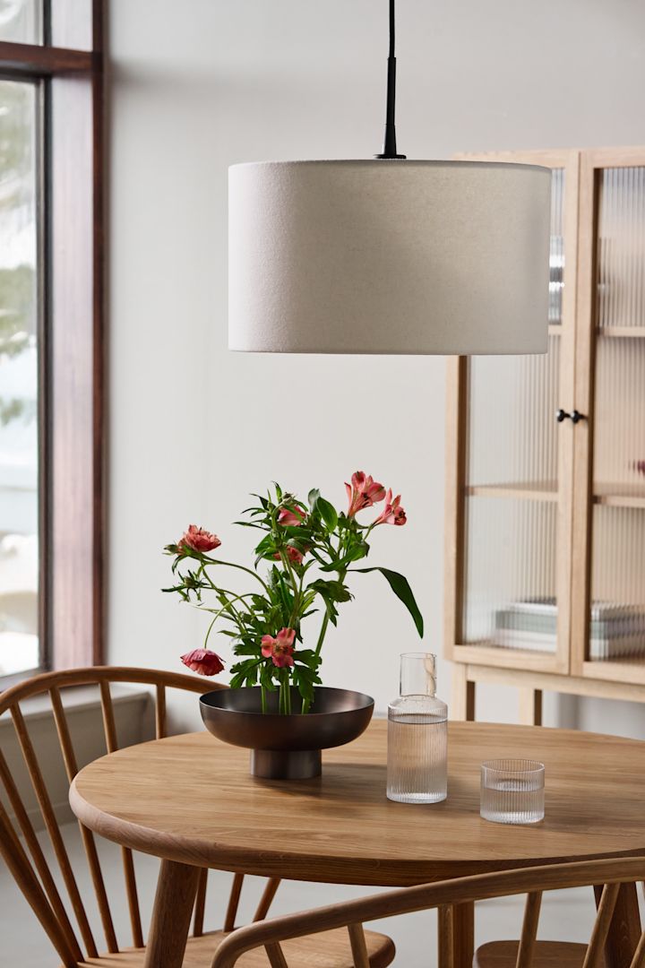 Ideas de iluminación en el comedor para resaltar la mesa. Aquí puedes ver la lámpara de techo Soft de Belid colgando sobre una mesa de comedor de madera.