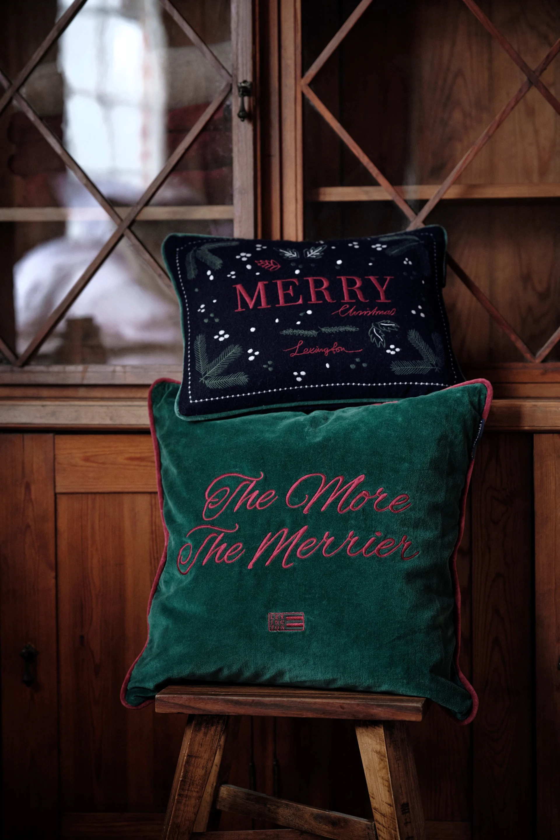 Los cojines son una decoración navideña muy popular en 2025: aquí vemos dos cojines festivos de Lexington sobre un taburete.