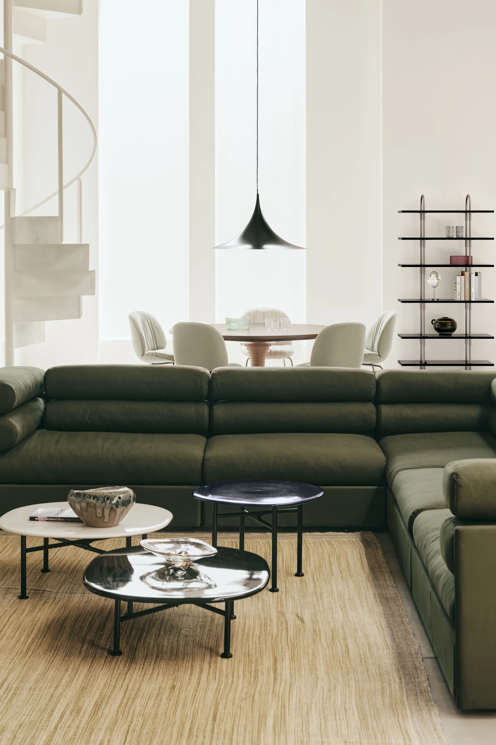 La lámpara de techo adecuada para el salón: aquí se puede ver la lámpara colgante Semi de Gubi en un salón decorado con muebles verdes.