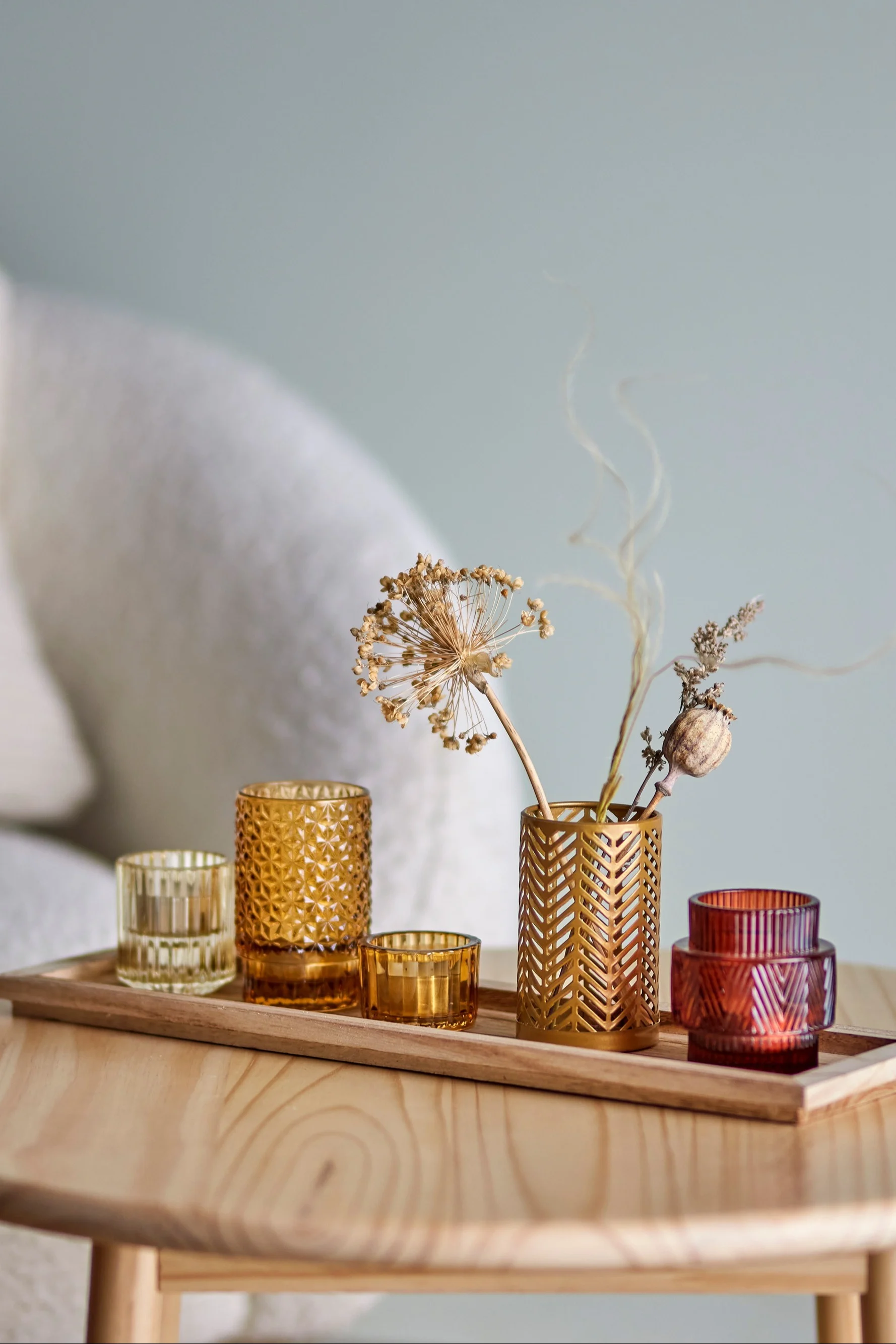 La decoración boho perfecta: la bandeja Sanga con farolillos en tonos amarillos y rojos de Bloomingville sobre una mesa de salón.