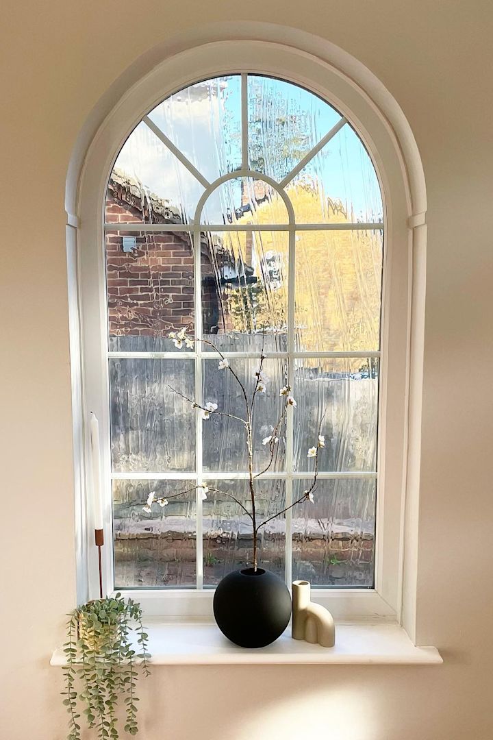 Aquí puedes ver la bonita ventana arqueada con alféizar de @abrysonhouse, que está decorada con candelabros y el jarrón de bolas negras de Cooee Design con flores primaverales.