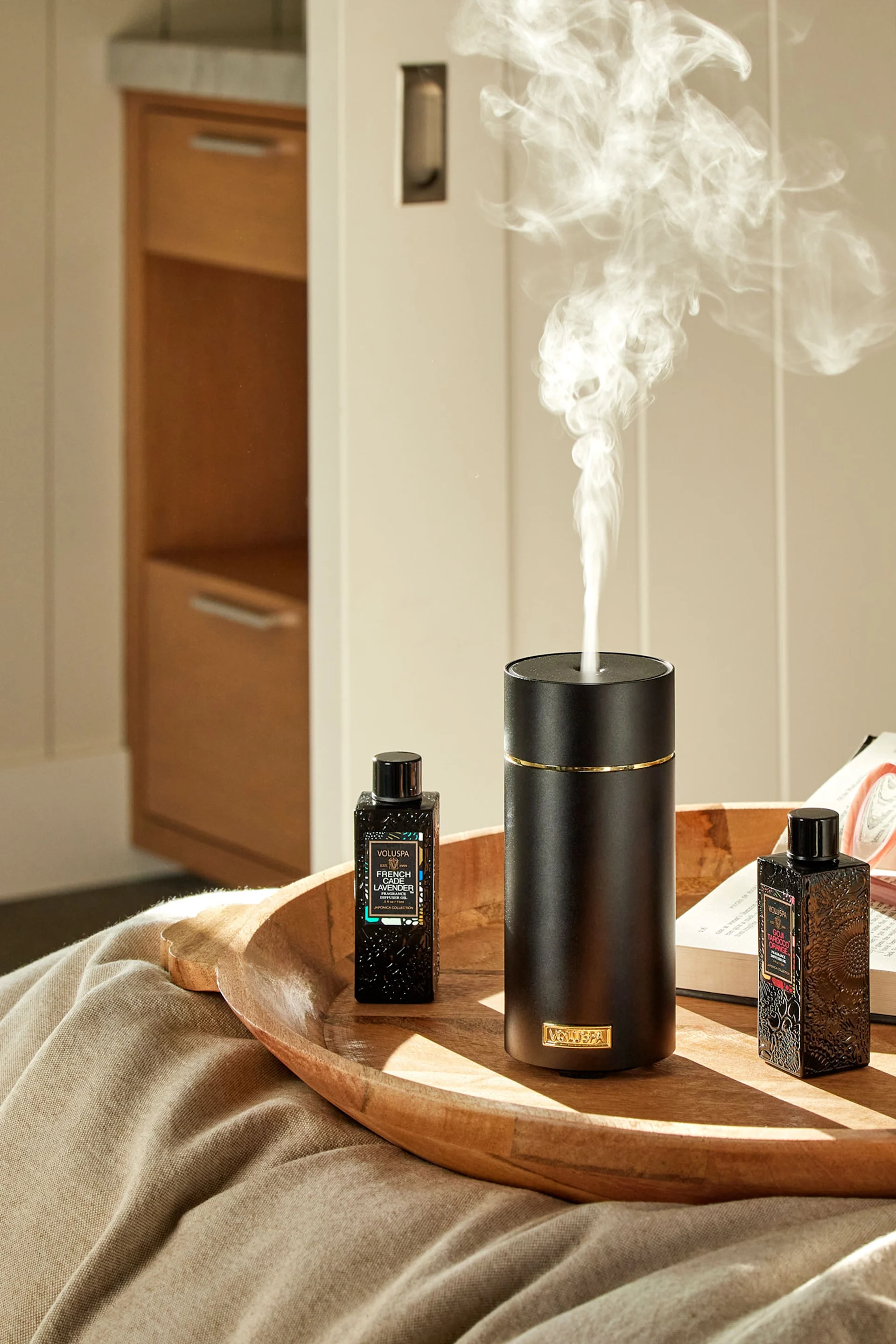 El difusor de piedra gris de Volant se encuentra sobre una pila de libros delante de un espejo, con una planta al lado. Regálalo el Día de la Madre para crear una sensación de spa.