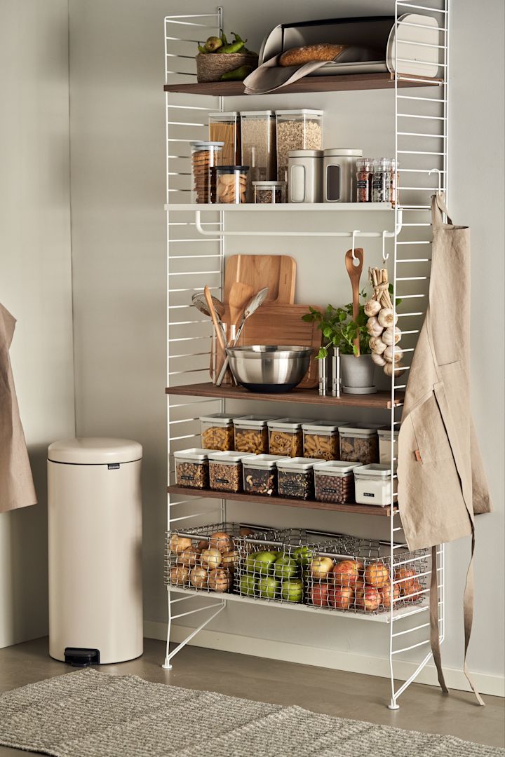 Una despensa perfectamente organizada con una estantería String y los tarros de almacenaje Brabantia.