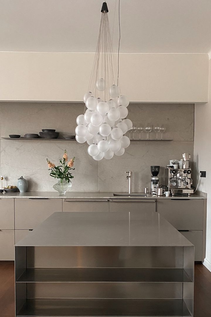 Renueva tu hogar con un diseño de iluminación moderna. Aquí puedes ver la lámpara de techo Stochastic de Luce Plan, una colección de esferas de vidrio colgando en grupo sobre una mesa de trabajo de acero inoxidable.