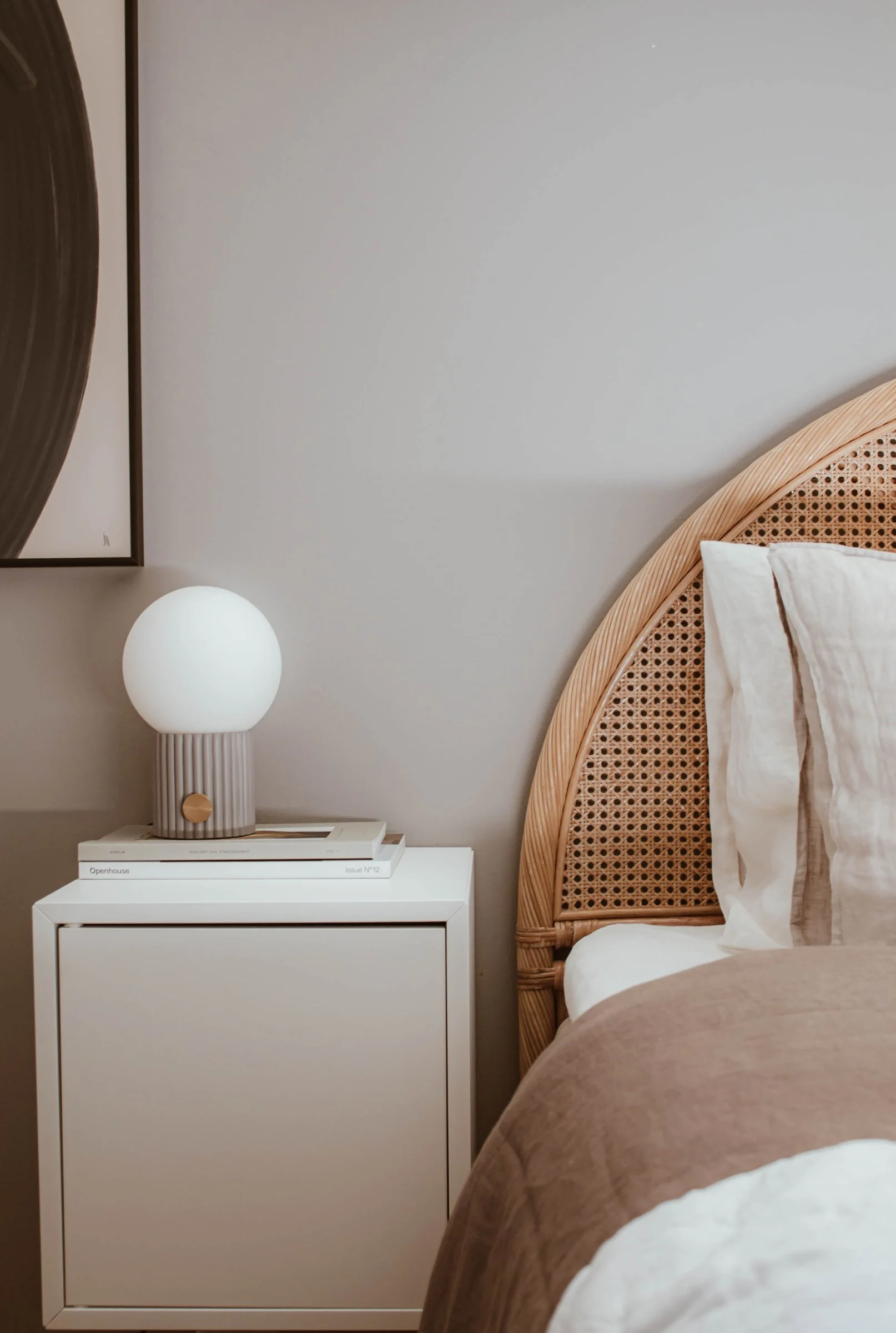 La lámpara de sobremesa gris Hubble se coloca sobre la mesilla de noche de un dormitorio amueblado en estilo boho.