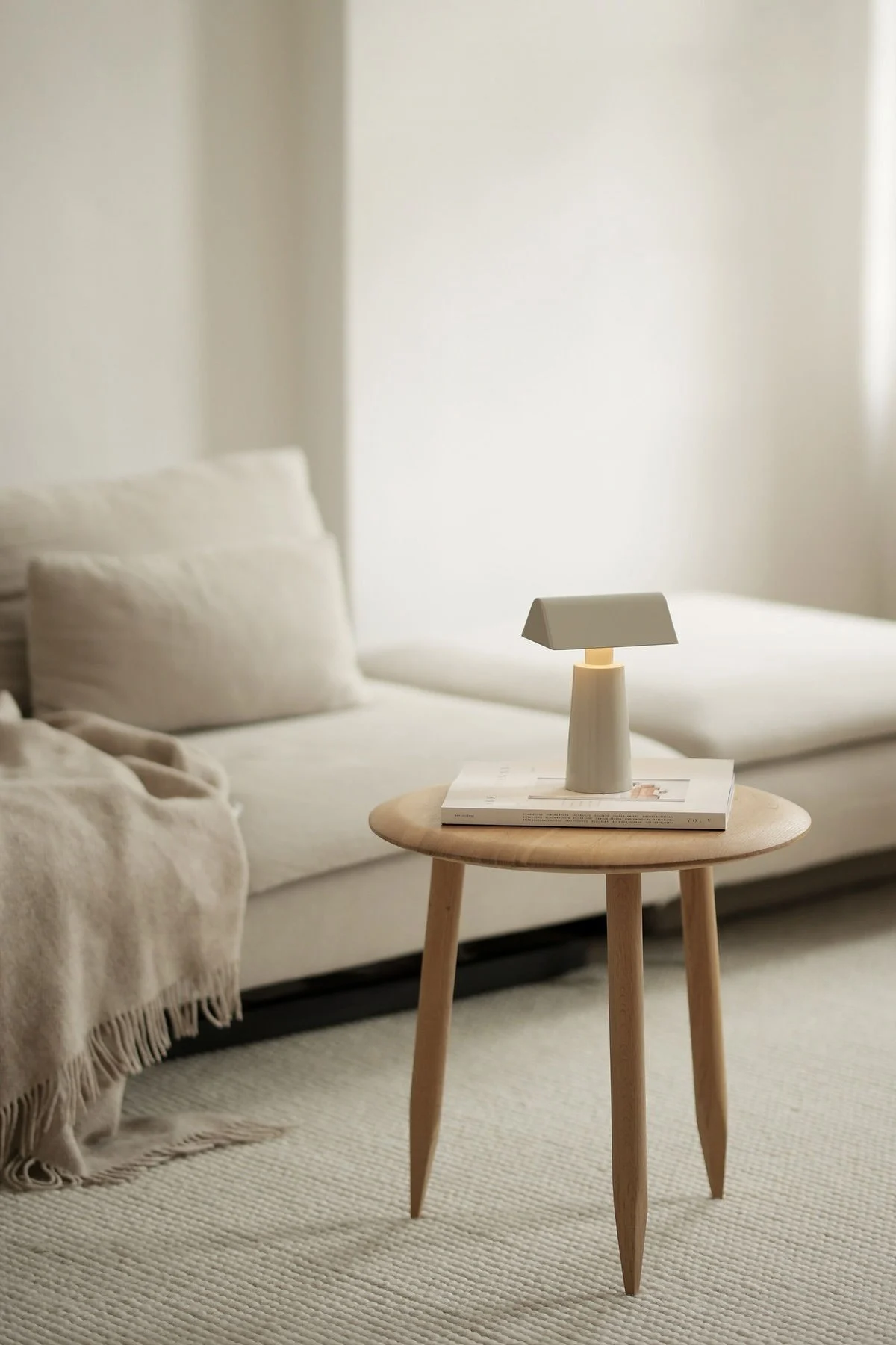 El estilo de vida Lagom se caracteriza por los colores sutiles. Aquí puedes ver el salón beige de @b.wohnbar con un sofá y una mesa delante, sobre la que se alza la lámpara de mesa Caret MF1 de &Tradition.