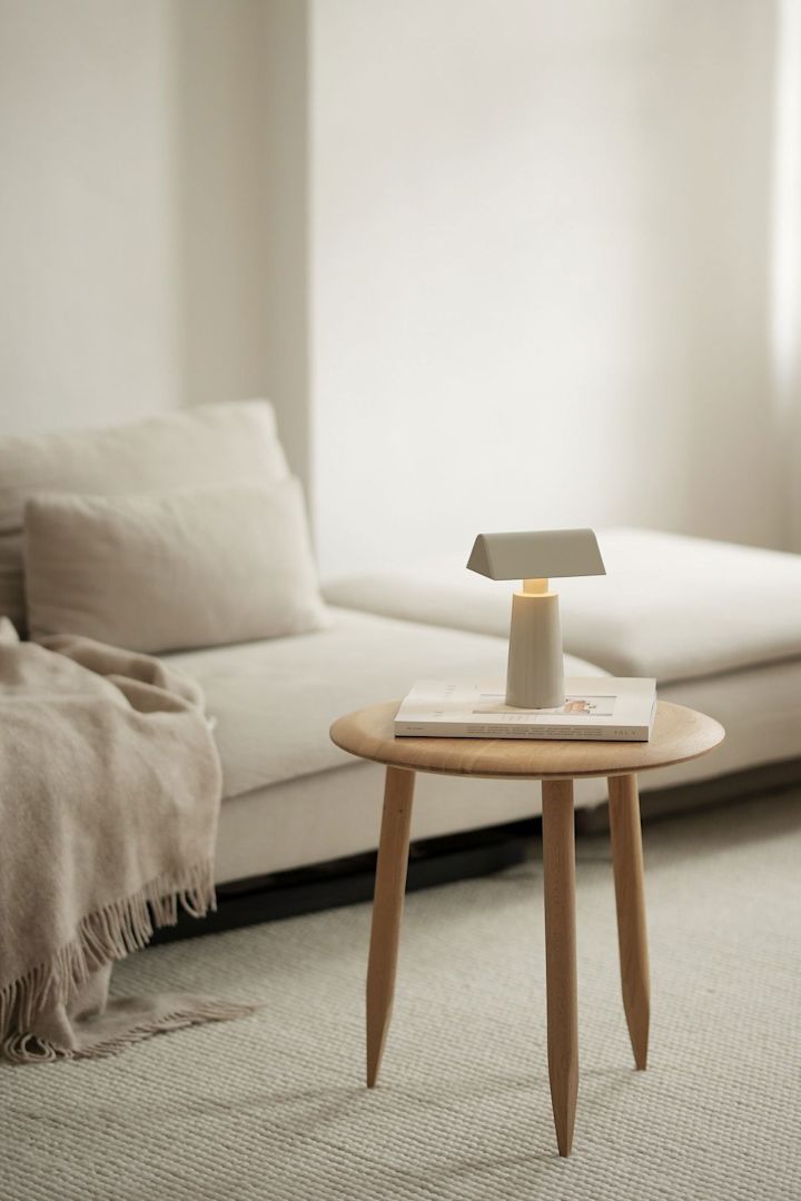 El estilo de vida Lagom se caracteriza por los colores sutiles. Aquí puedes ver el salón beige de @b.wohnbar con un sofá y una mesa delante, sobre la que se alza la lámpara de mesa Caret MF1 de &Tradition.