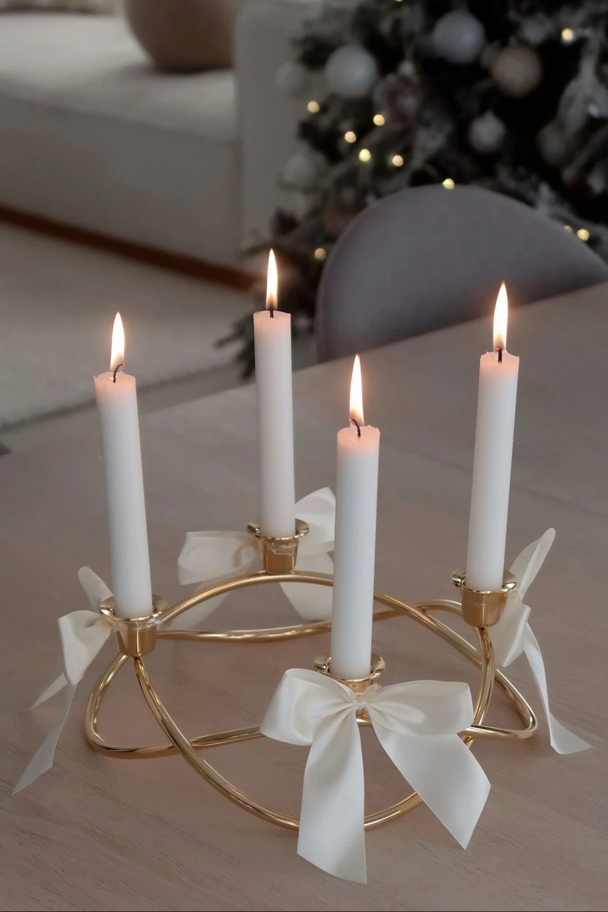 El portavelas Season de Georg Jensen, dorado y decorado con lazos, está sobre una mesa.