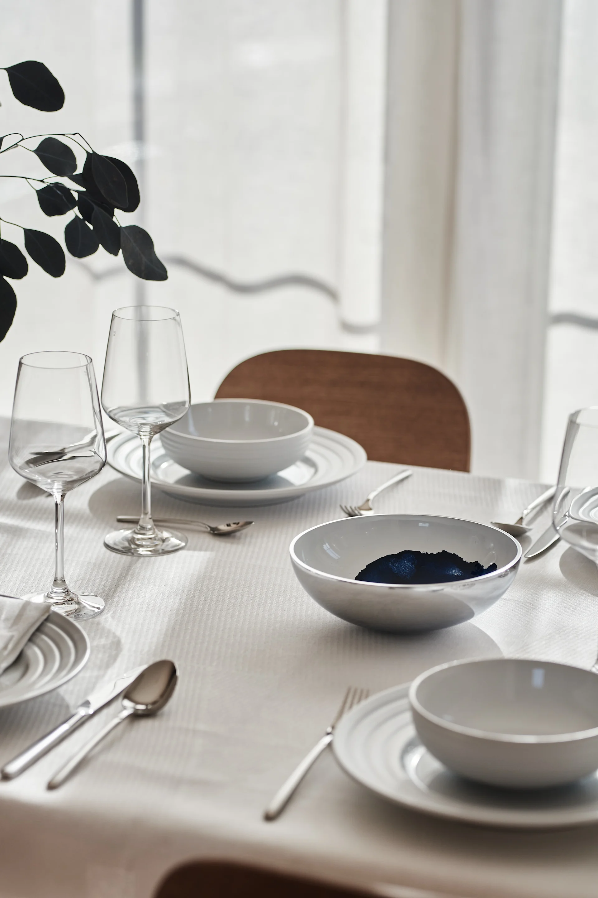Una mesa blanca con porcelana de NJRD y servilletas y mantel de lino de Scandi Living.