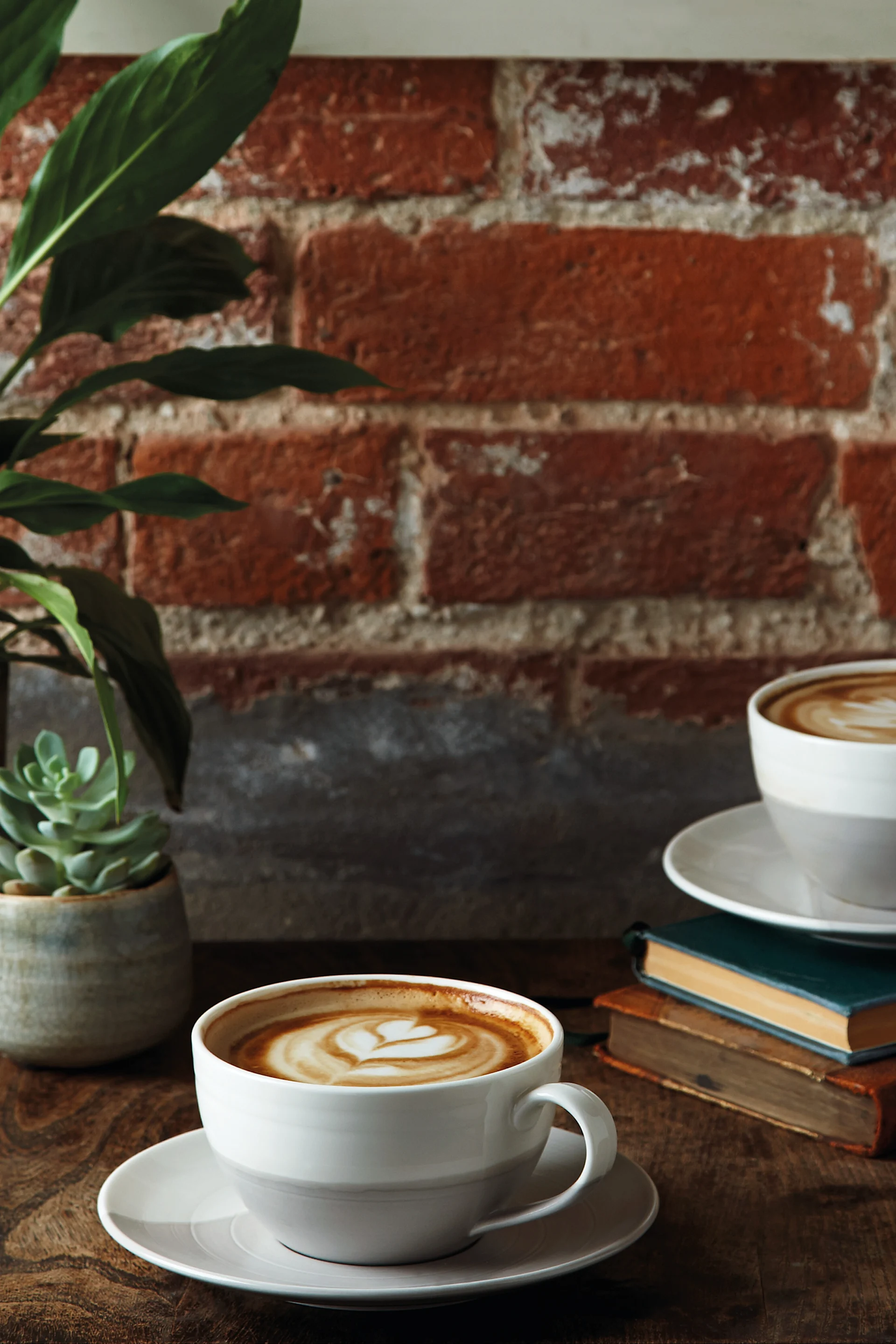 La taza de café espresso Coffee & More de color gris se encuentra sobre una tabla de madera encima de una cama, con un croissant al lado.