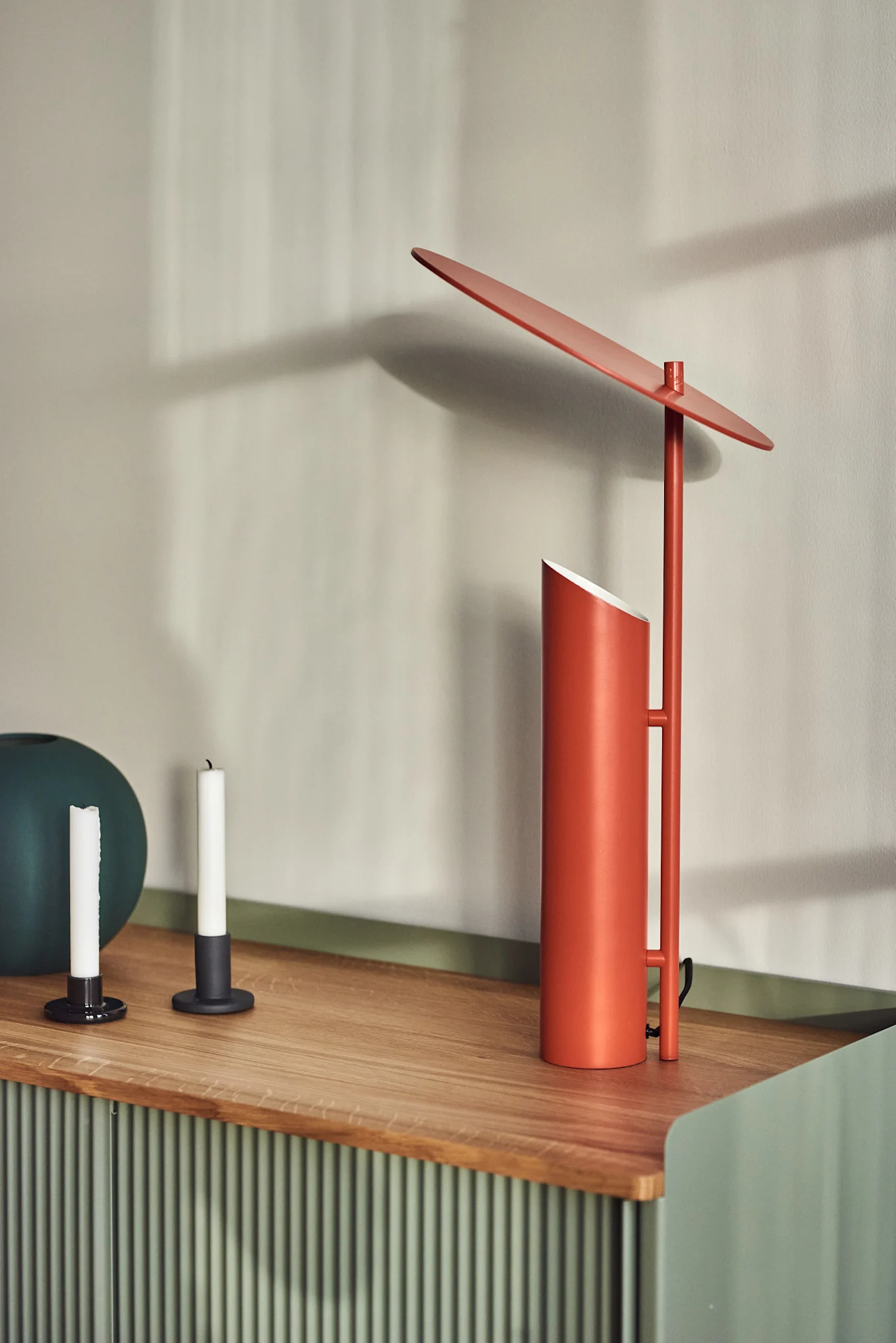 Sobre una cómoda se encuentra la lámpara de mesa Reflect en rojo, diseñada por Verner Panton para Verpan.