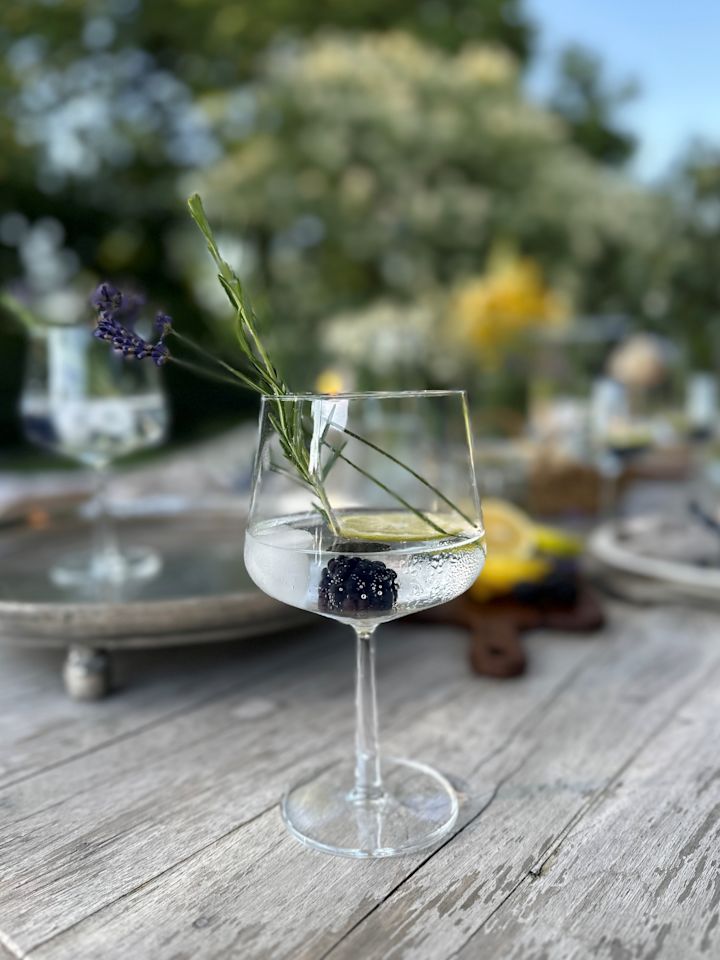 Una copa de cóctel tipo gin-tonic con un cóctel y lima. 