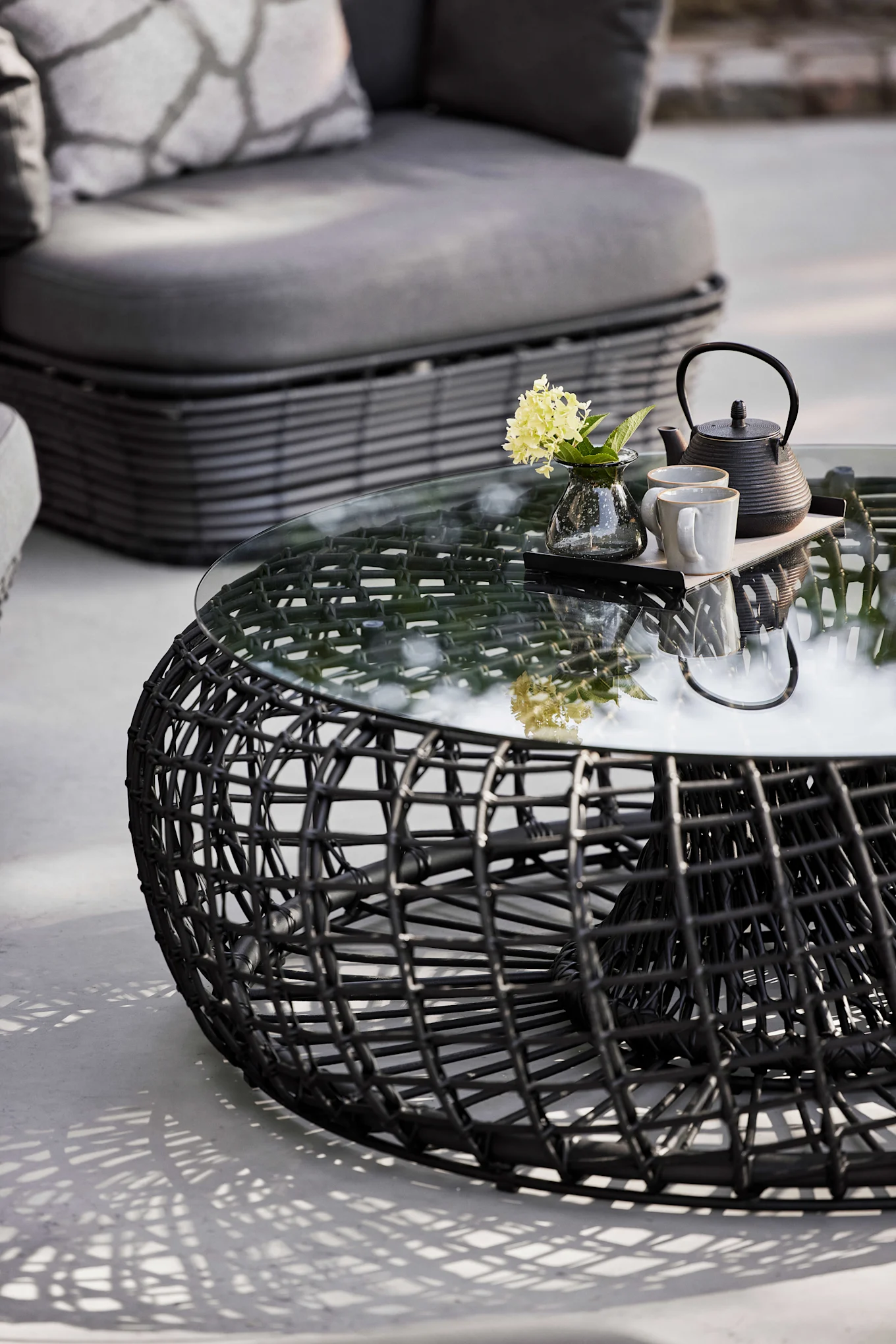 La mesa Nest de Cane-line en negro es de cristal y aluminio e impresiona por su forma redonda, sin duda una tendencia en muebles de jardín para 2025.