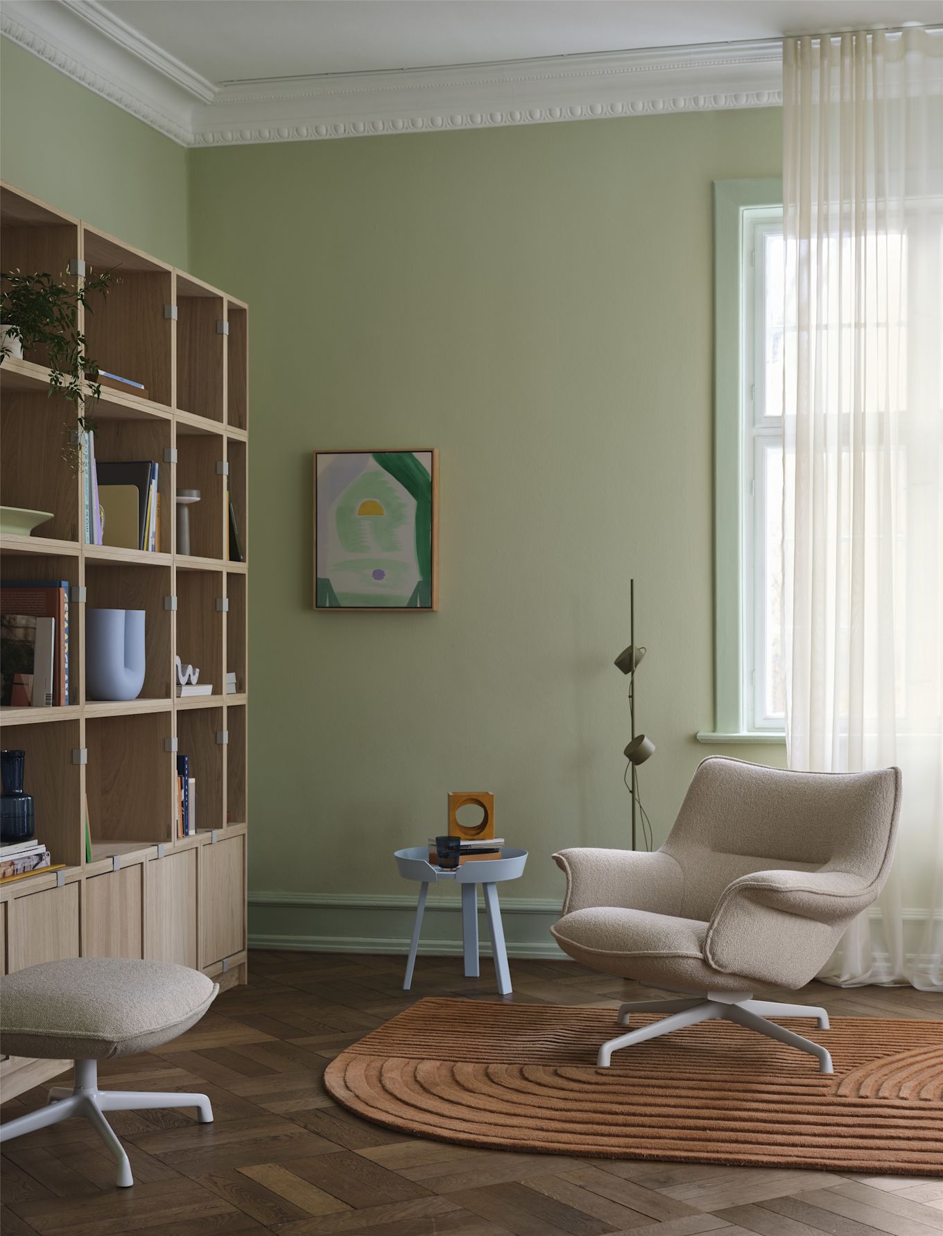 El sillón Doze de Muuto, de color beige, se encuentra frente a una estantería en un salón acogedor.