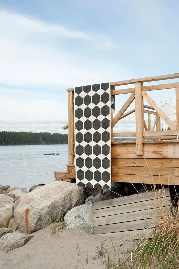 Alfombra de exterior:alfombra de exterior Anna de Brita Sweden en negro limpiada y colgada sobre la barandilla del balcón.