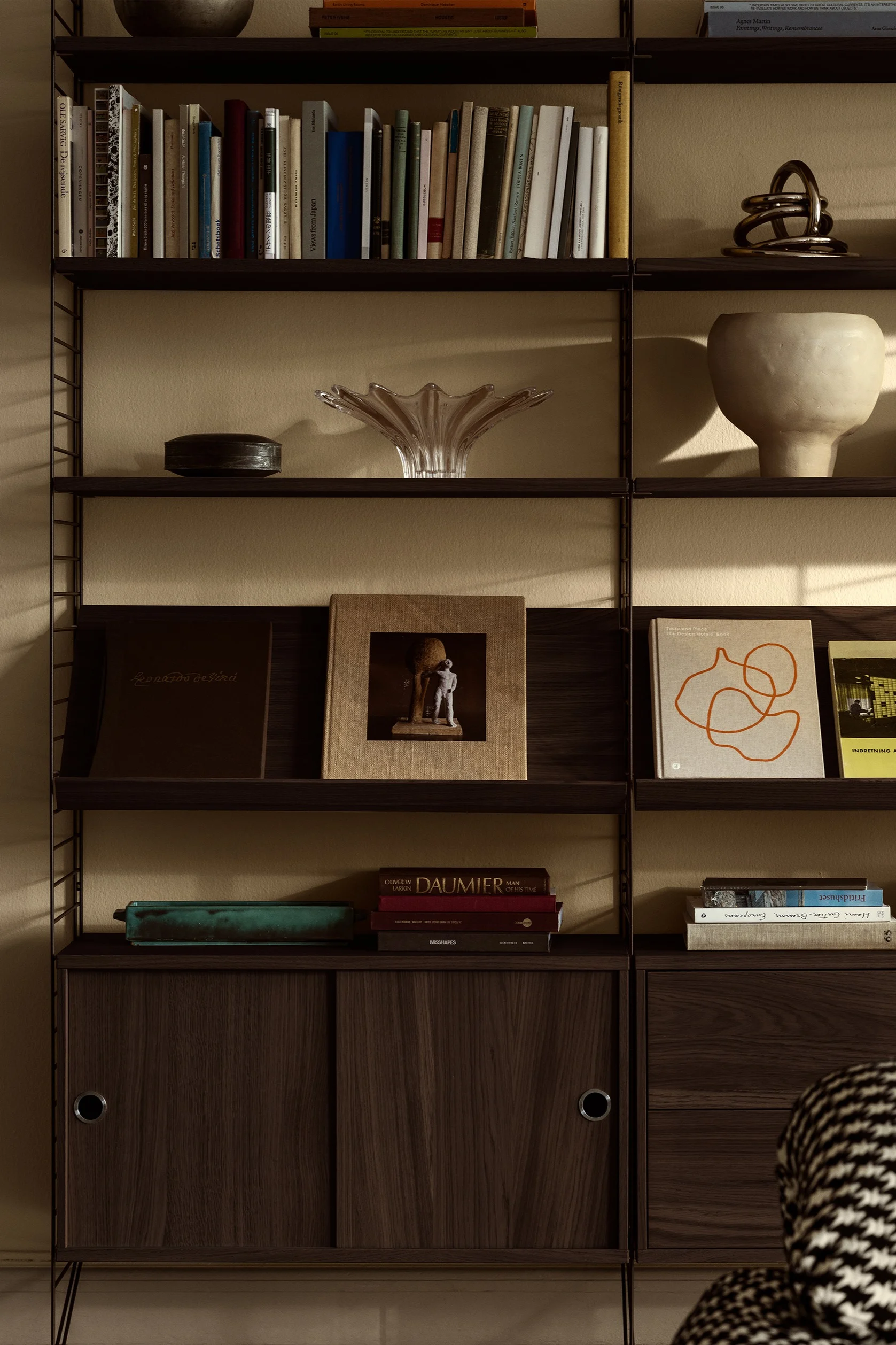 El sistema de estanterías String es perfecto para decorar paredes. Aquí puedes ver el sistema de estanterías con detalles personales, como libros y cuencos.