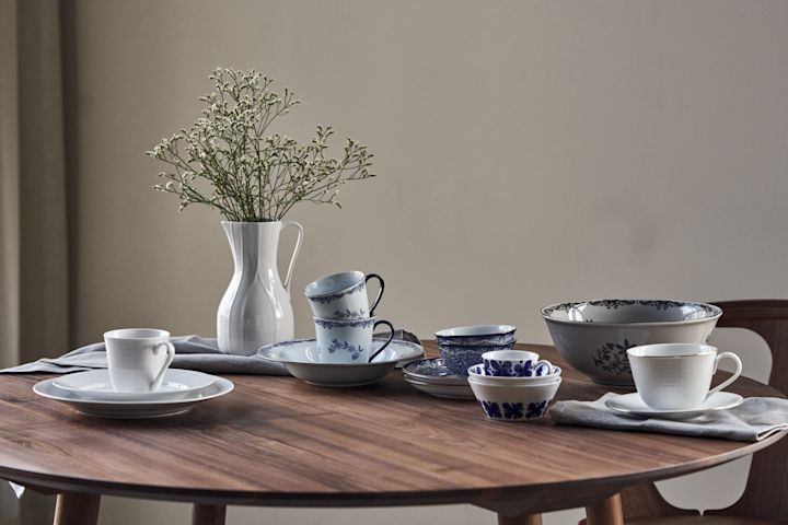 Los clásicos de porcelana de Rörstrand se alinean en una mesa redonda: Mon Amie, Swedish Grace, Ostindia en azul y negro y la jarra Pli Blanc. 