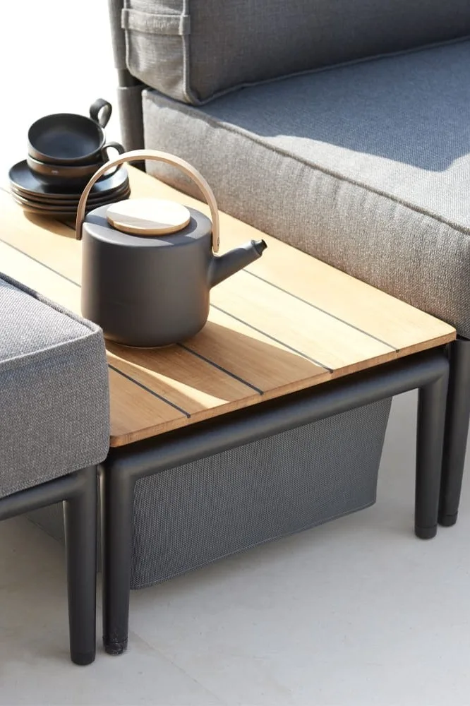 La mesa de centro Conic de Cane-line no sólo sirve como superficie de almacenaje, sino que también ofrece espacio para guardar mantas o cojines, por lo que es, con razón, una de las tendencias en muebles de jardín para 2025.