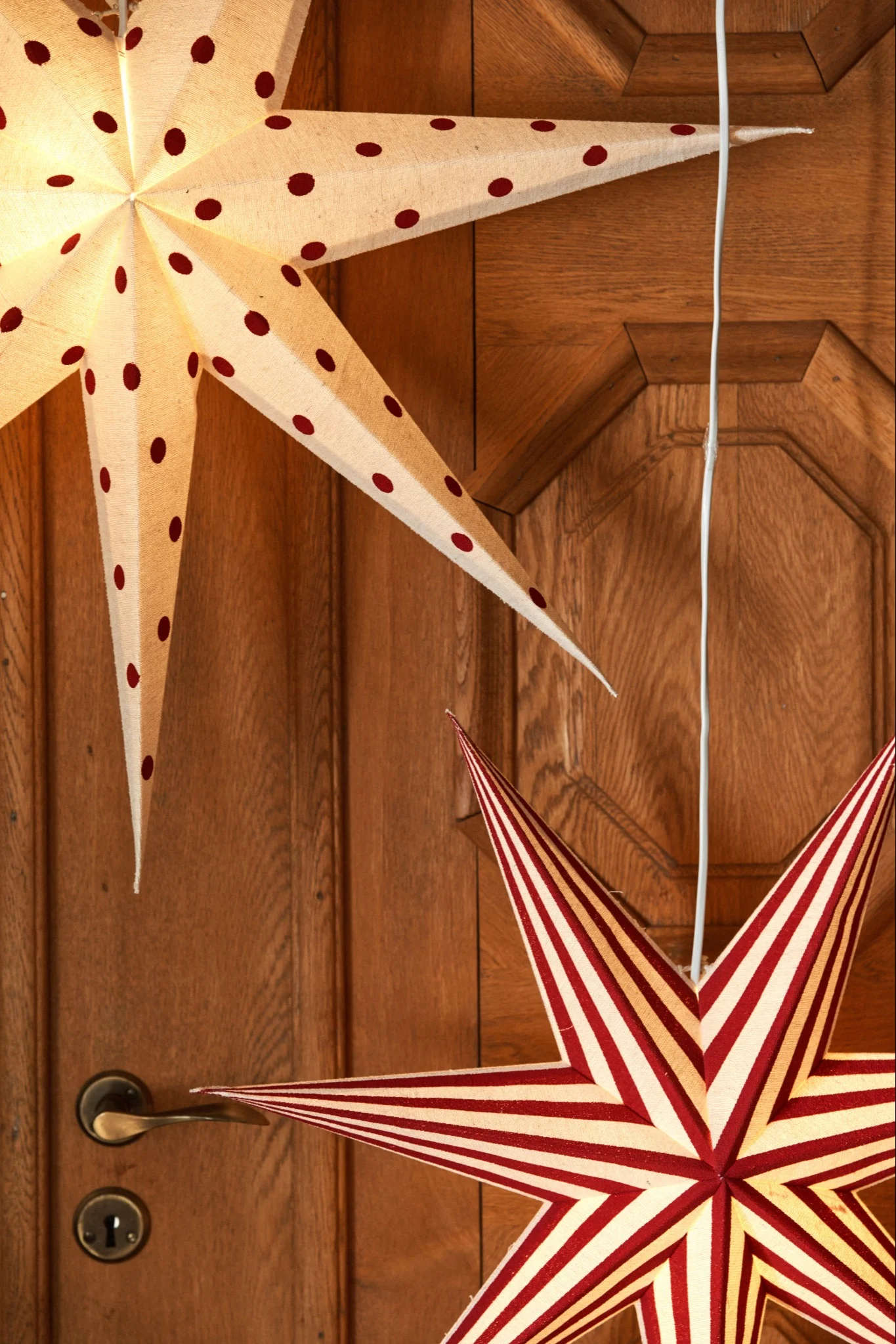 Ventana blanca con una decoración de estrella blanca y roja de lunares, encajada en una rústica pared de madera roja.