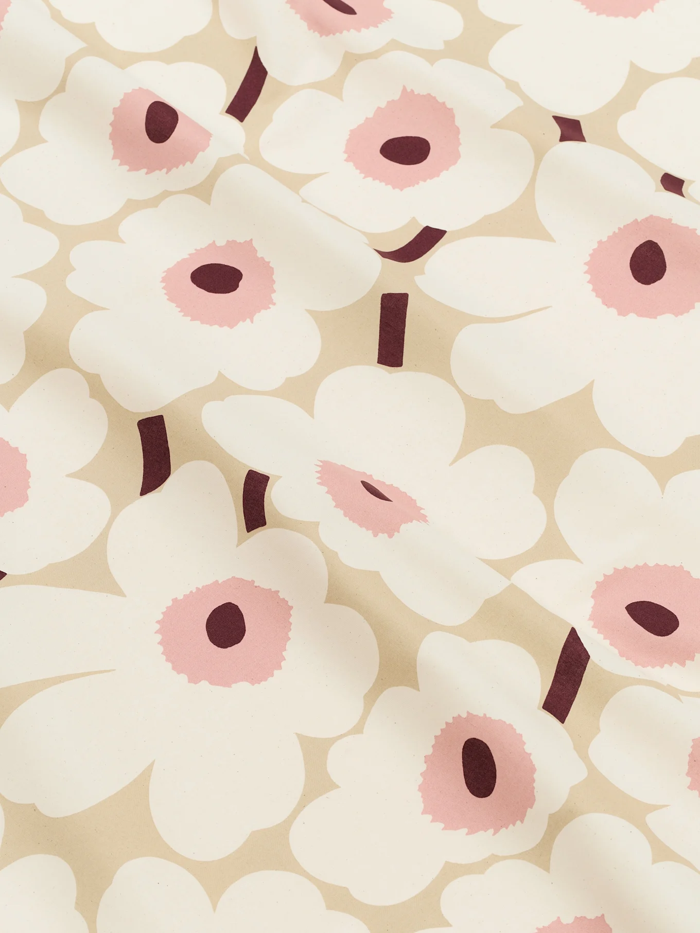 Primer plano de una tela beige claro estampada con grandes flores blancas estilizadas con centros rosas y tallos burdeos oscuros.