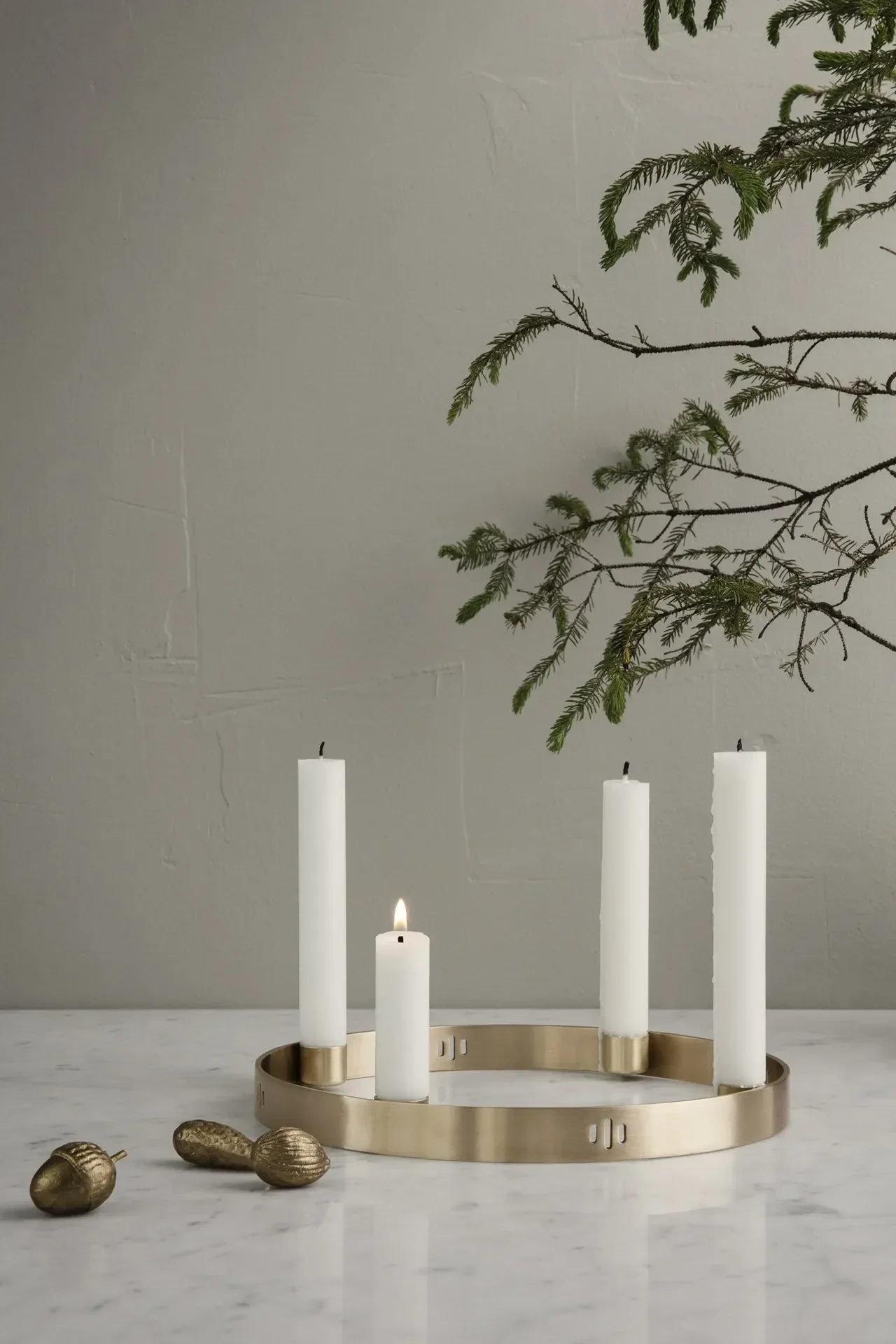 En un ambiente minimalista, el portavelas Circle de Ferm Living, en latón, está sobre una mesa.