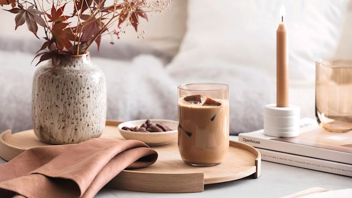 Lagom: una mesa otoñal con un jarrón y una vela, el centro de atención es un vaso largo Like con café helado de Villeroy & Boch.