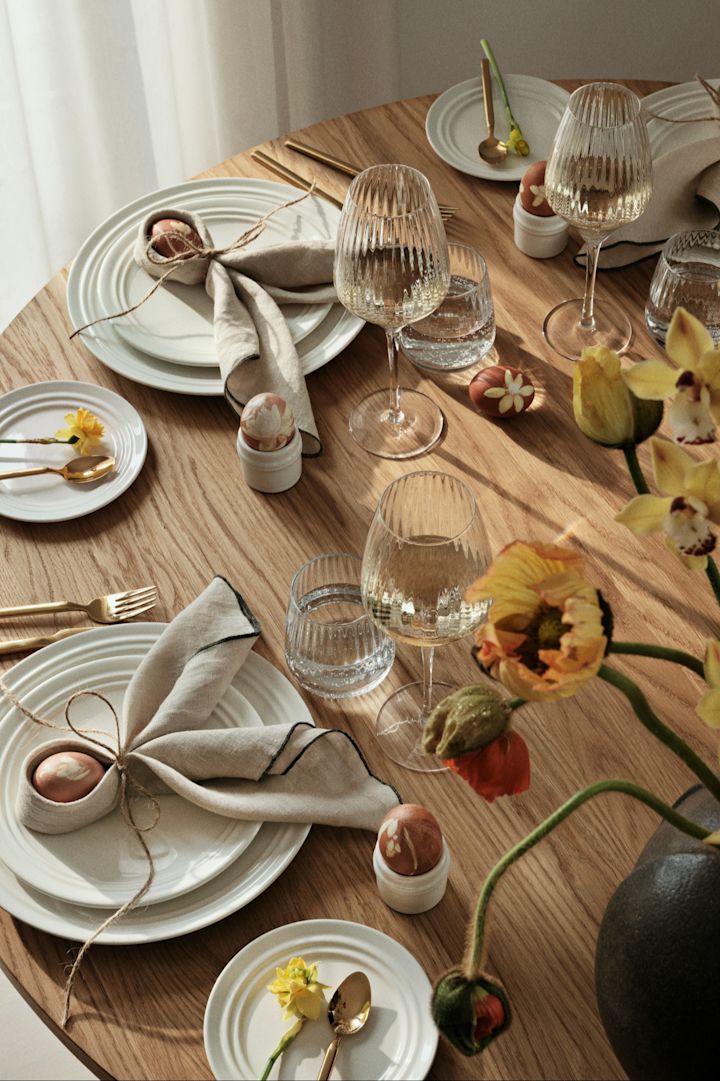 La mesa de comedor está decorada con vajilla, cristalería y cubiertos de Broste Copenhagen, y las servilletas están dobladas en forma de orejas de conejo.