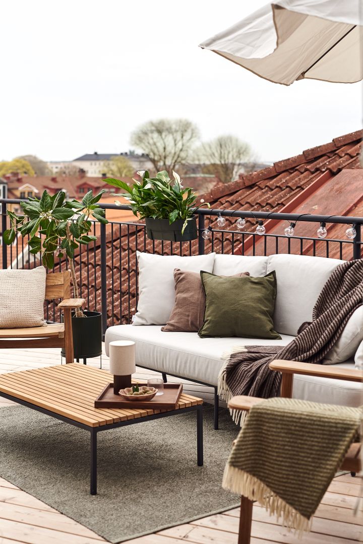 ¡Decora tu balcón con textiles suaves como esta manta de lana de NJRD para crear una sensación acogedora!