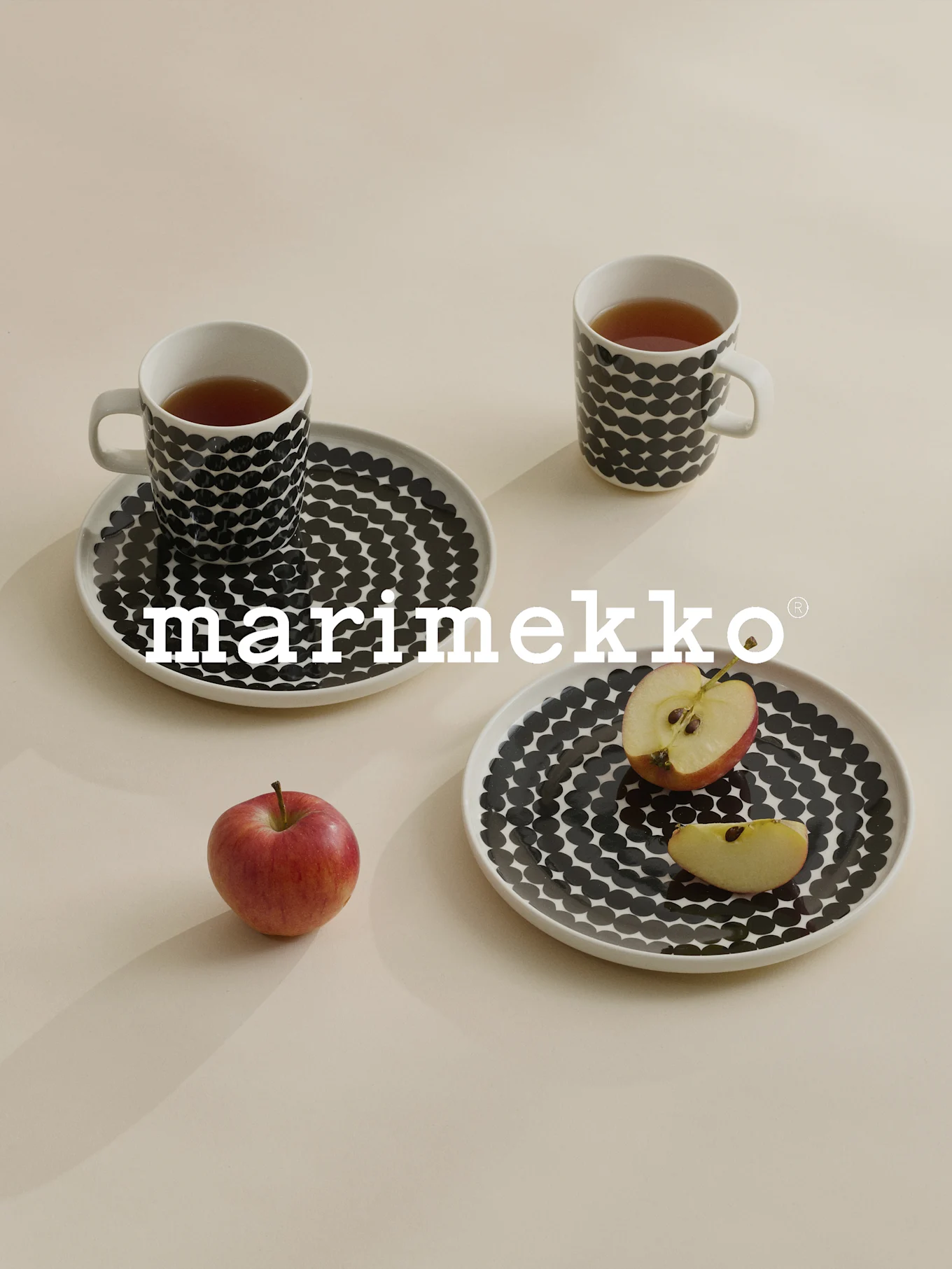 Dos tazas y platos con lunares negros, té, manzana roja, logotipo de Marimekko.