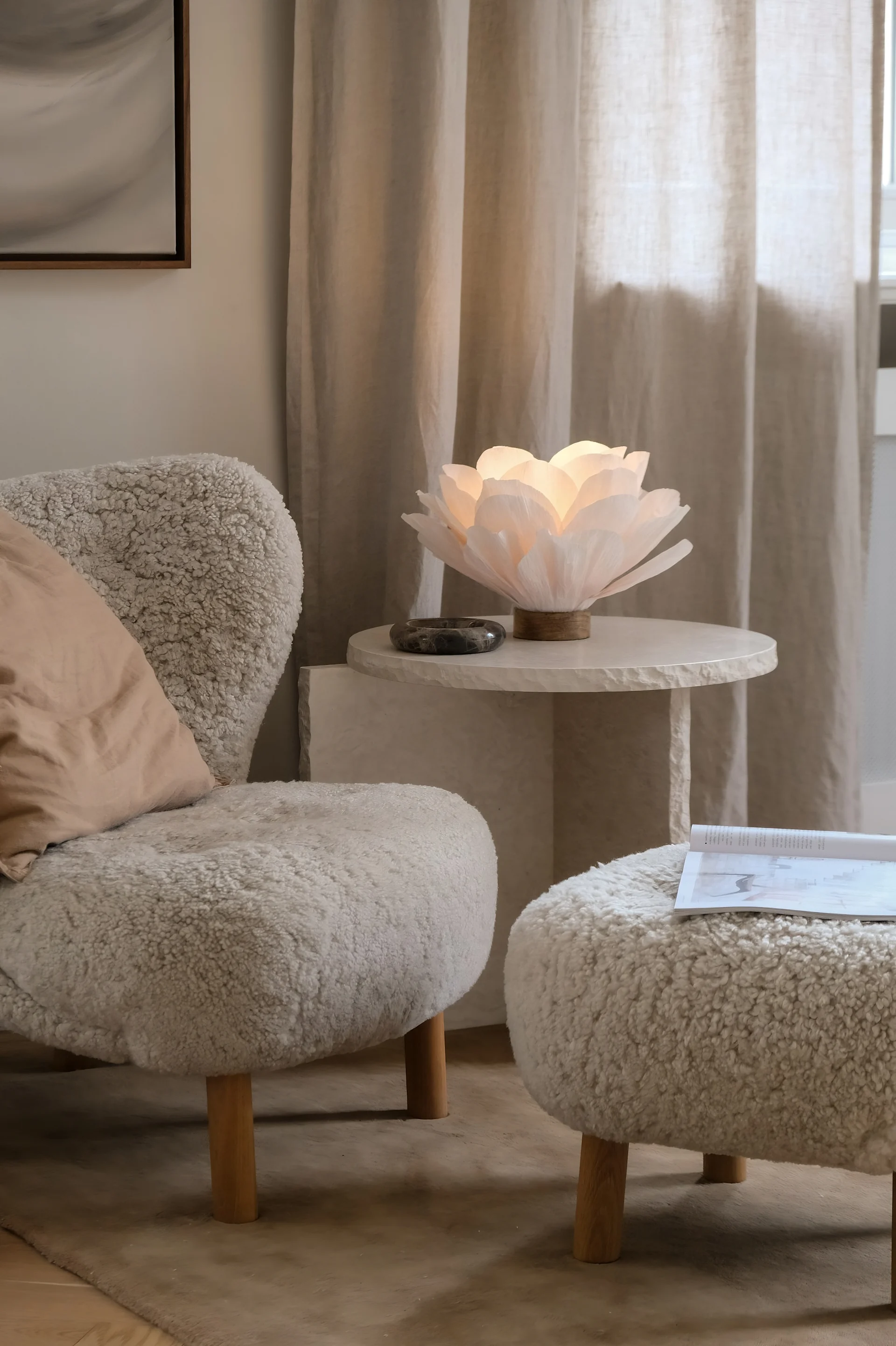 Un salón decorado en tonos beige con un sillón Little Petra y una mesa de centro de mármol, decorada con la lámpara de mesa Lisa de Watt & Veke.