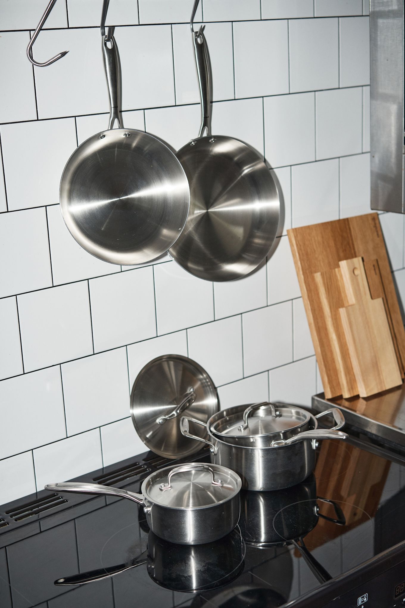 Las sartenes limpias de Nordwik están colgadas en una cocina de azulejos, con las ollas de Nordwik debajo del fogón.