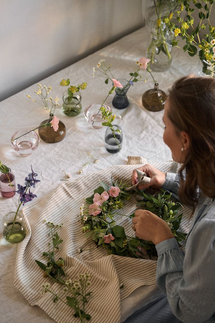 Una mujer hace una corona de flores a mano, una idea esencial de las fiestas de Midsummer suecas.