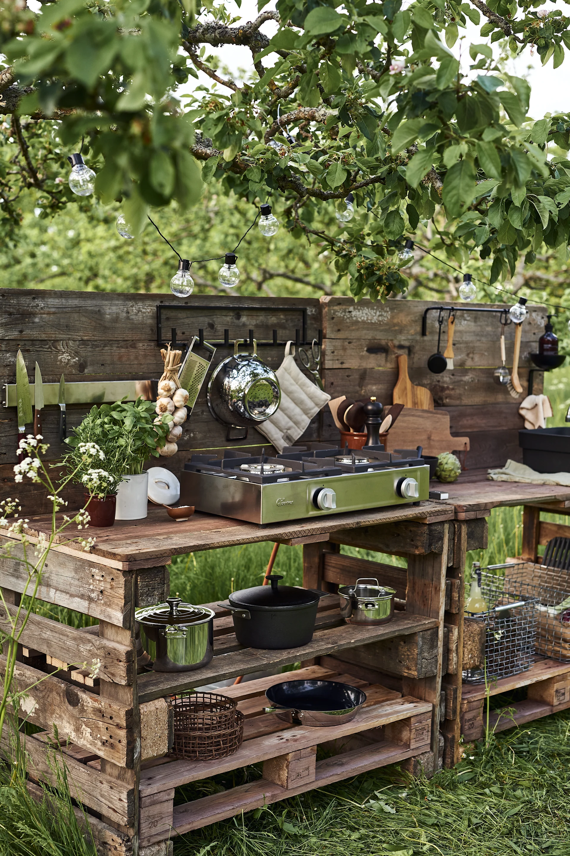 Construye tu propia cocina de exterior sencilla con palets de madera; aquí puedes ver la estación de cocina equipada con estantes para organizar tus ollas, sartenes y utensilios.