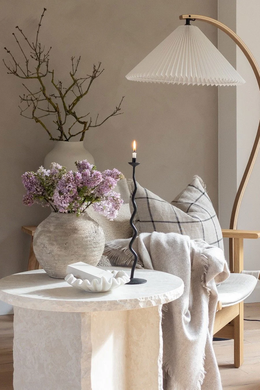 Una mesa de centro de mármol decorada con flores, un cuenco y un portavelas, todo en un estilo rústico.