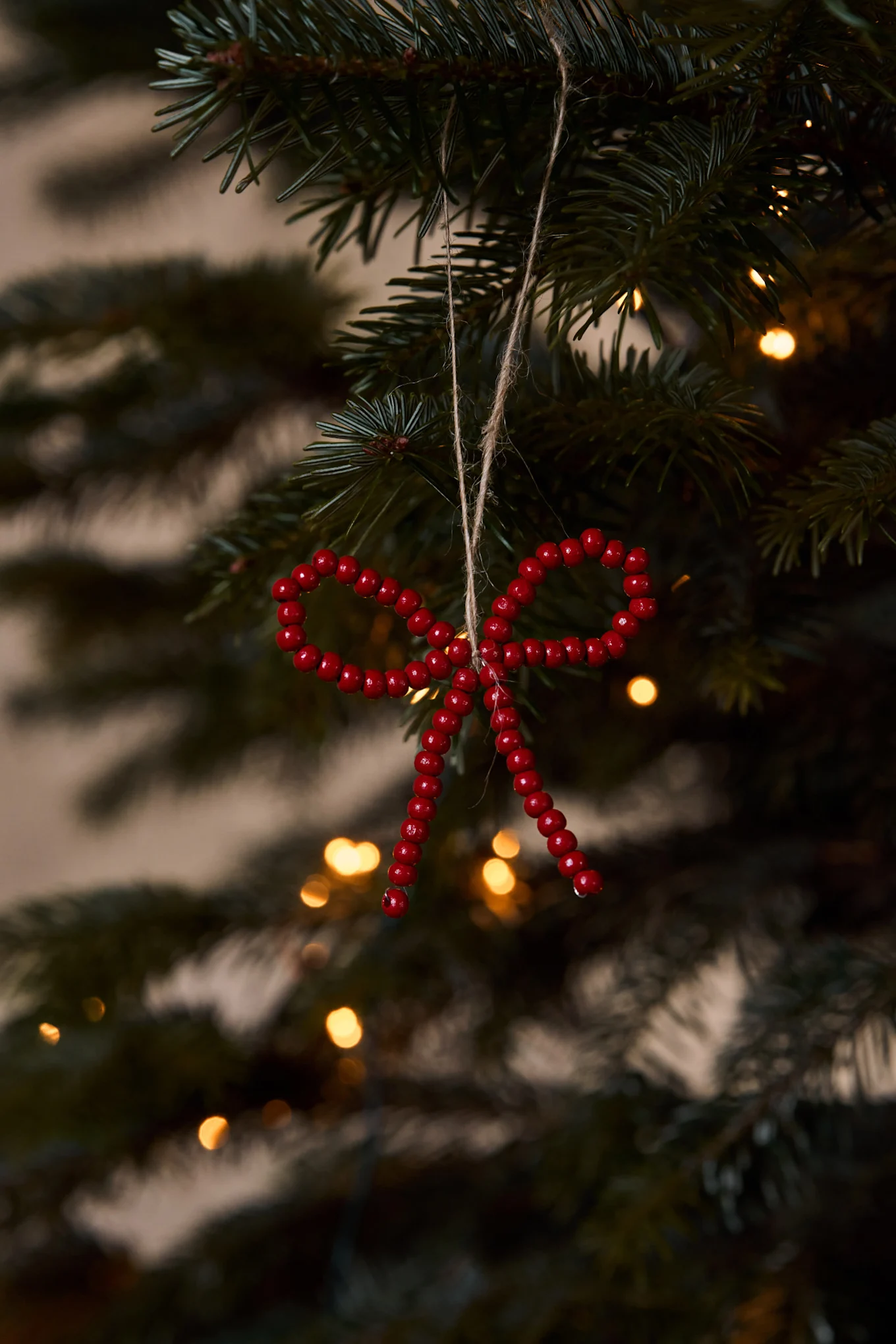Corona de Navidad con un gran lazo de terciopelo rojo en una puerta de madera roja desgastada con ramas de pino escarchadas.