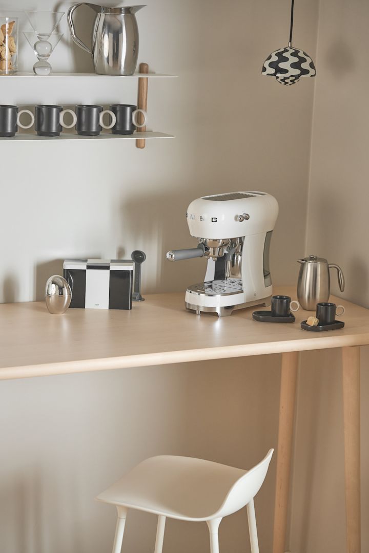 La cafetera de Smeg, que puedes ver aquí en un rincón, es especialmente adecuada para un rincón del café en casa, con una lámpara Flowerpot de &tradition iluminando.