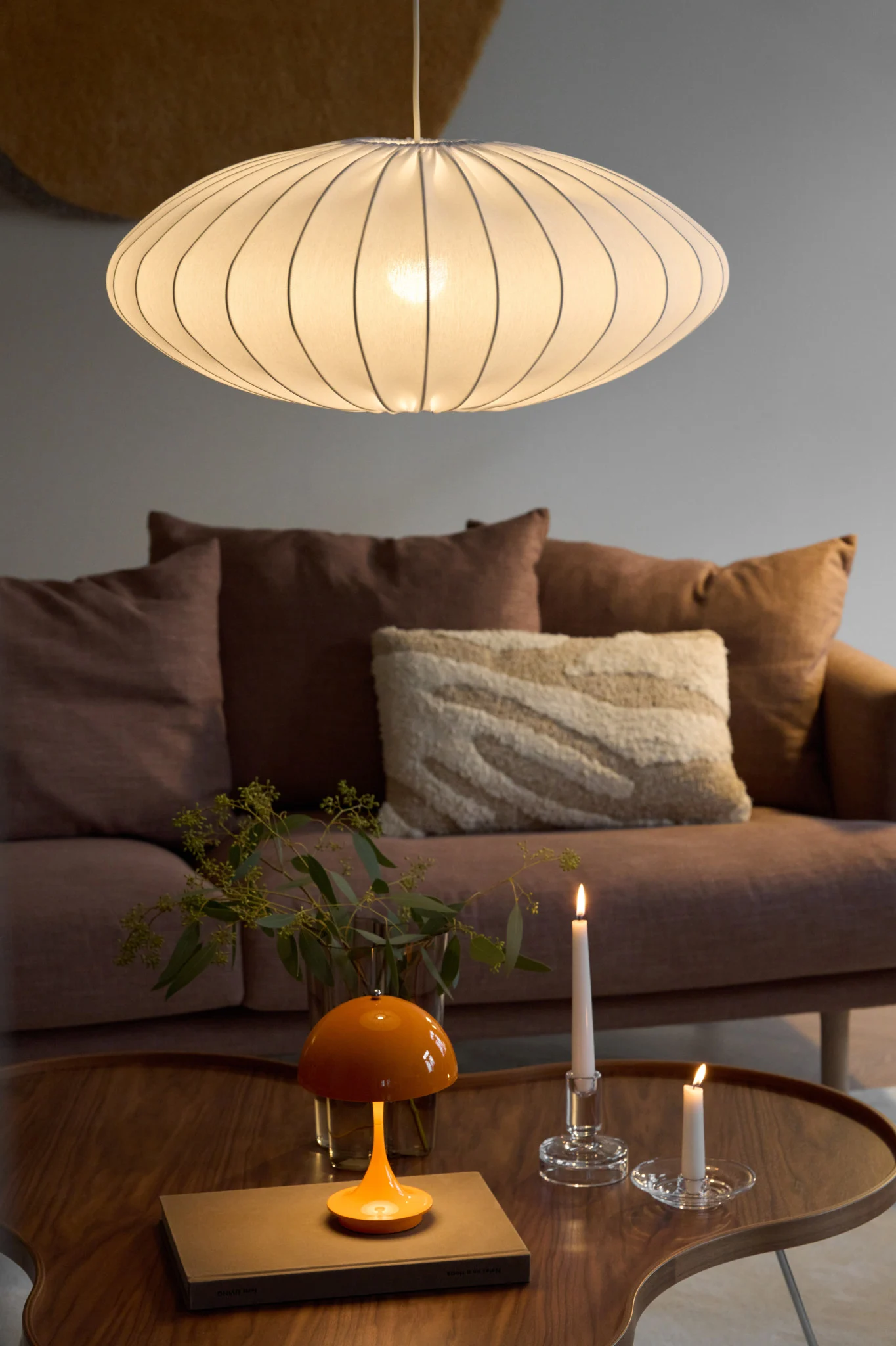 La lámpara colgante Ellipse con pantalla de tela de Watt & Veke está instalada en un salón decorado de forma acogedora.