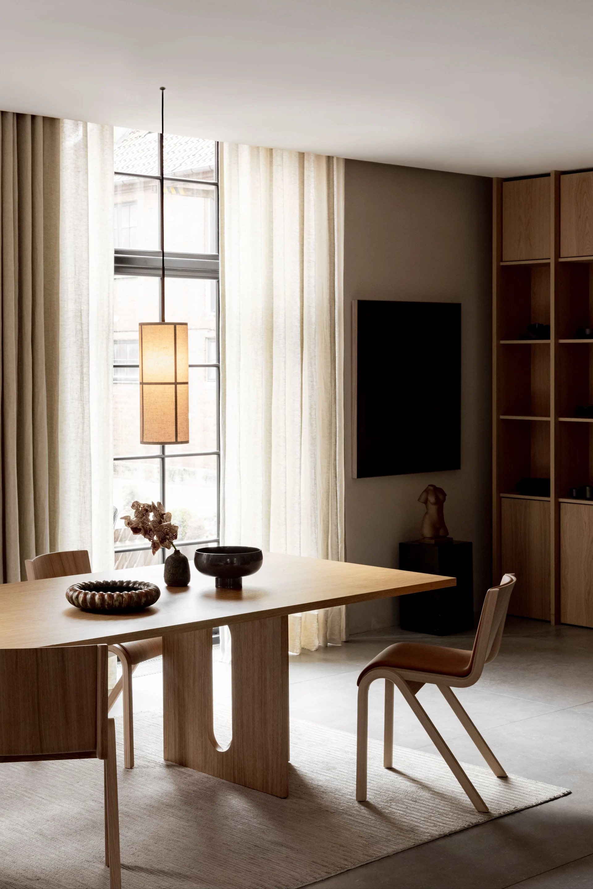 Un comedor con muebles de Audo Copenhagen está iluminado por la lámpara colgante Hashira.