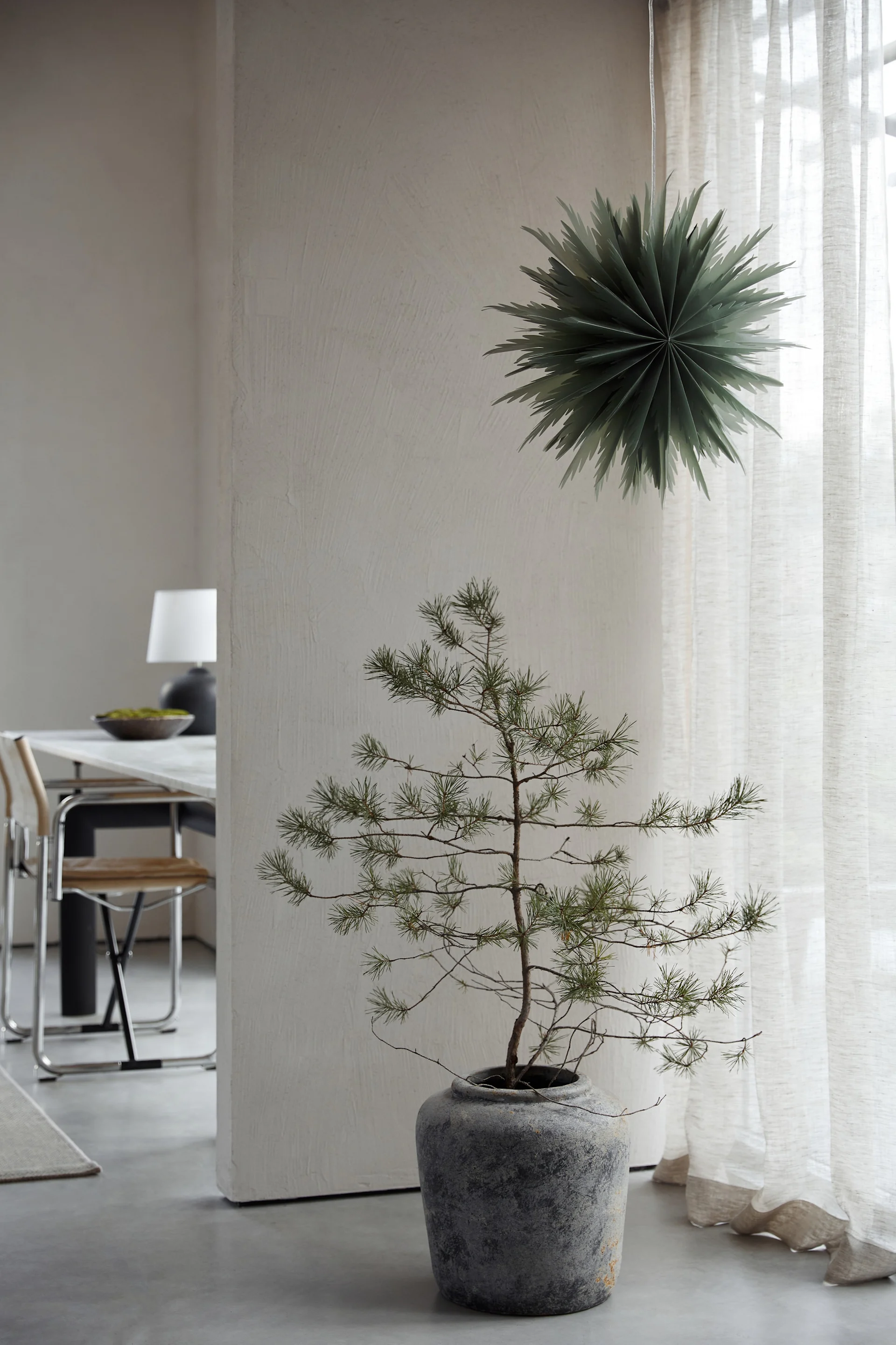 Decoración navideña minimalista como la estrella de papel Oslo de Watt & Veke. Aquí la vemos colgada en la ventana de un salón de tonos neutros.