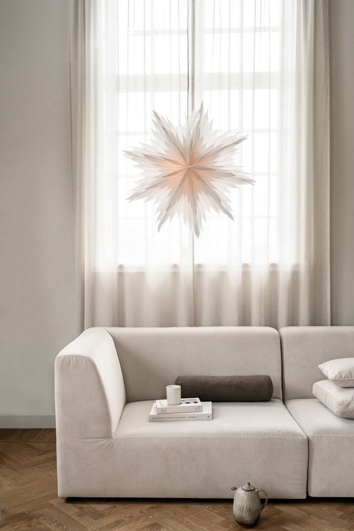 Decoración navideña minimalista como la estrella de papel Oslo de Watt & Veke. Aquí la vemos colgada en la ventana de un salón de tonos neutros.