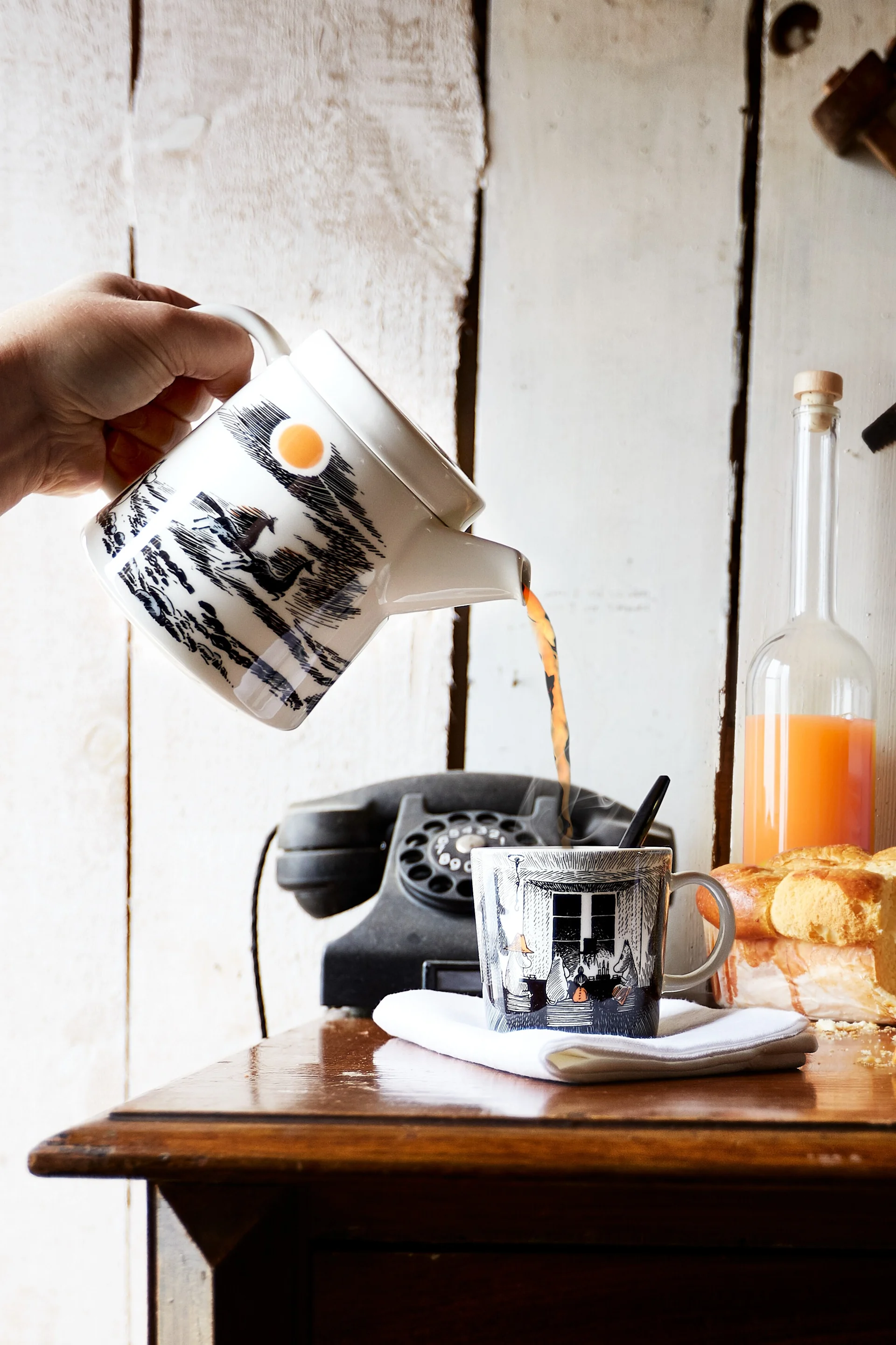 Lealtad al origen: alguien vierte té de la tetera a la taza Mumin.