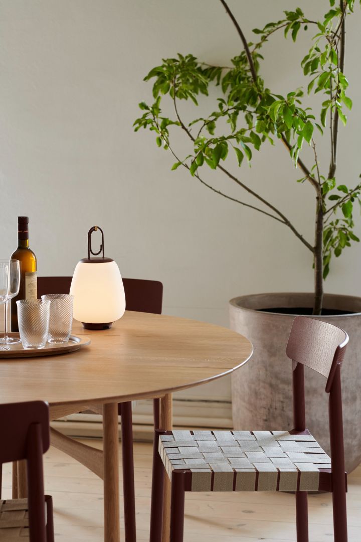 Japandi es el estilo que combina tanto los estilos interiores escandinavo como japonés, como se ve aquí con la lámpara Betty de &tradition colocada sobre una mesa de comedor junto a un pequeño árbol de interior.