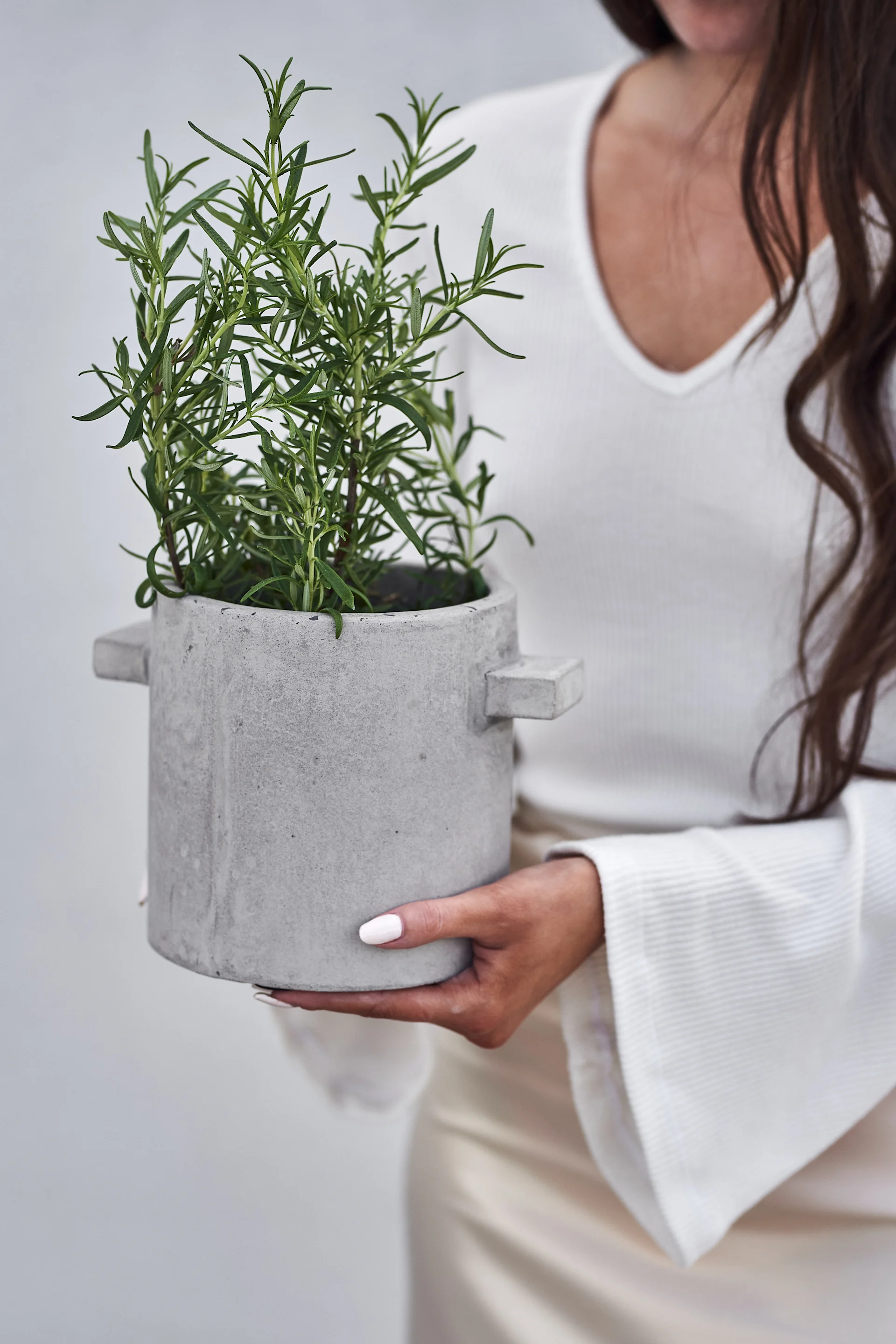 Las macetas para tus hierbas aromáticas en el balcón son imprescindibles en verano. Aquí puedes ver la maceta de hormigón de Serax con una planta de romero aromático. 