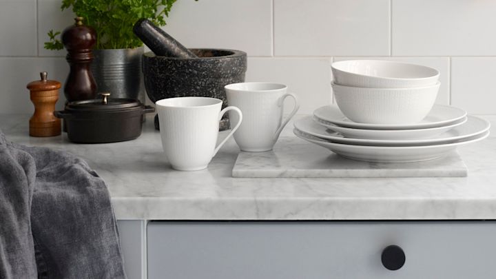 Taza de café con plato de cerámica blanca y canto gris.