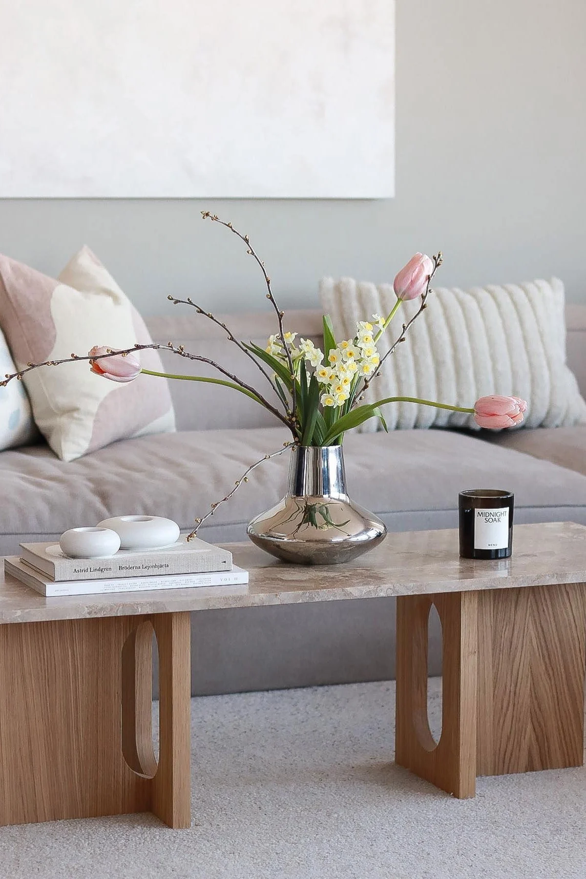 Una mesa de centro decorada al estilo primaveral por @picsbyellen: sobre la mesa Androgyne de Audo Copenhagen está el jarrón Henning Koppel de Georg Jensen en color cromado con tulipanes, acompañado de velas y portavelas.