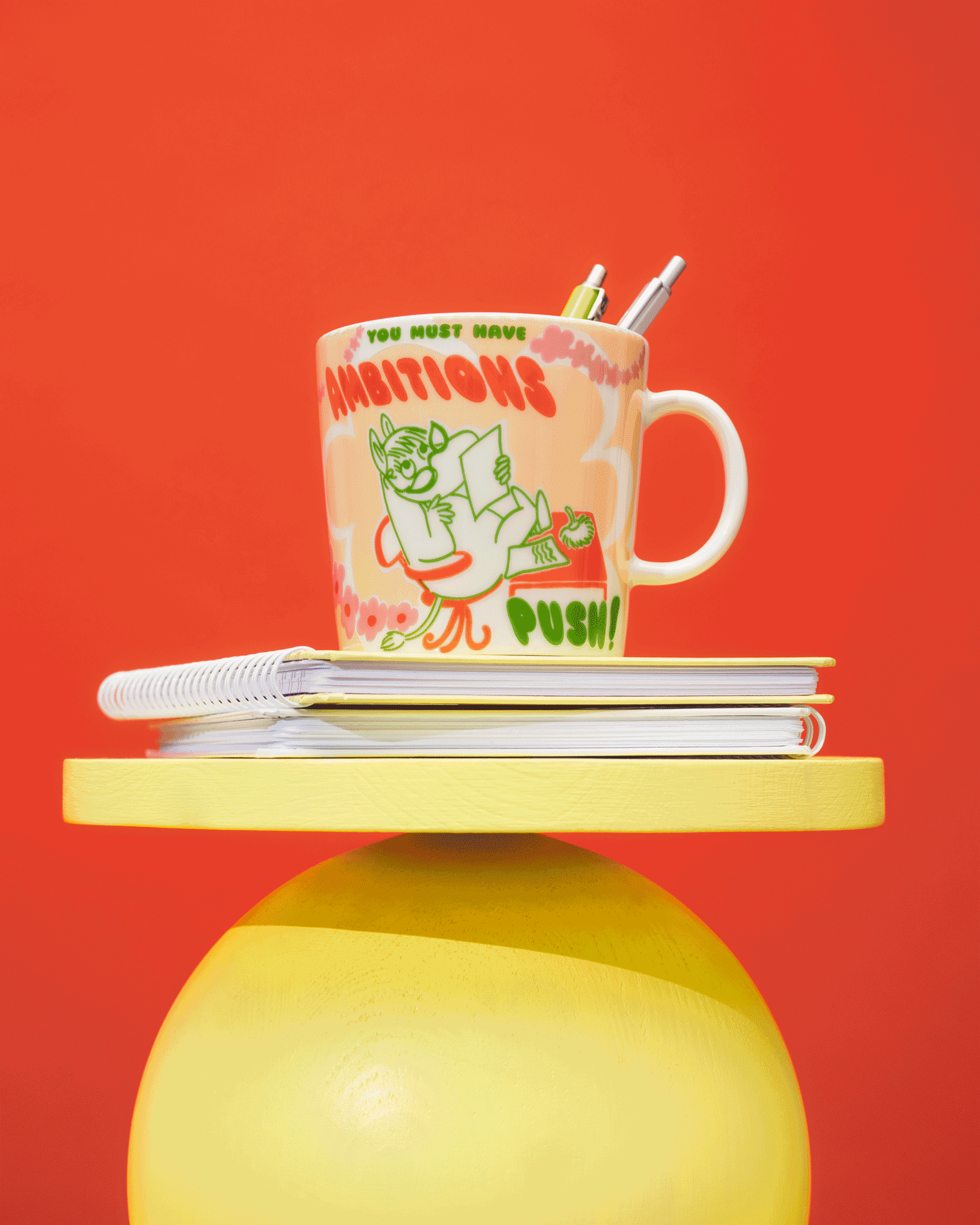 Cuatro tazas coloridas con motivos de Moomin en expositores amarillos y rojos sobre un fondo rojo.