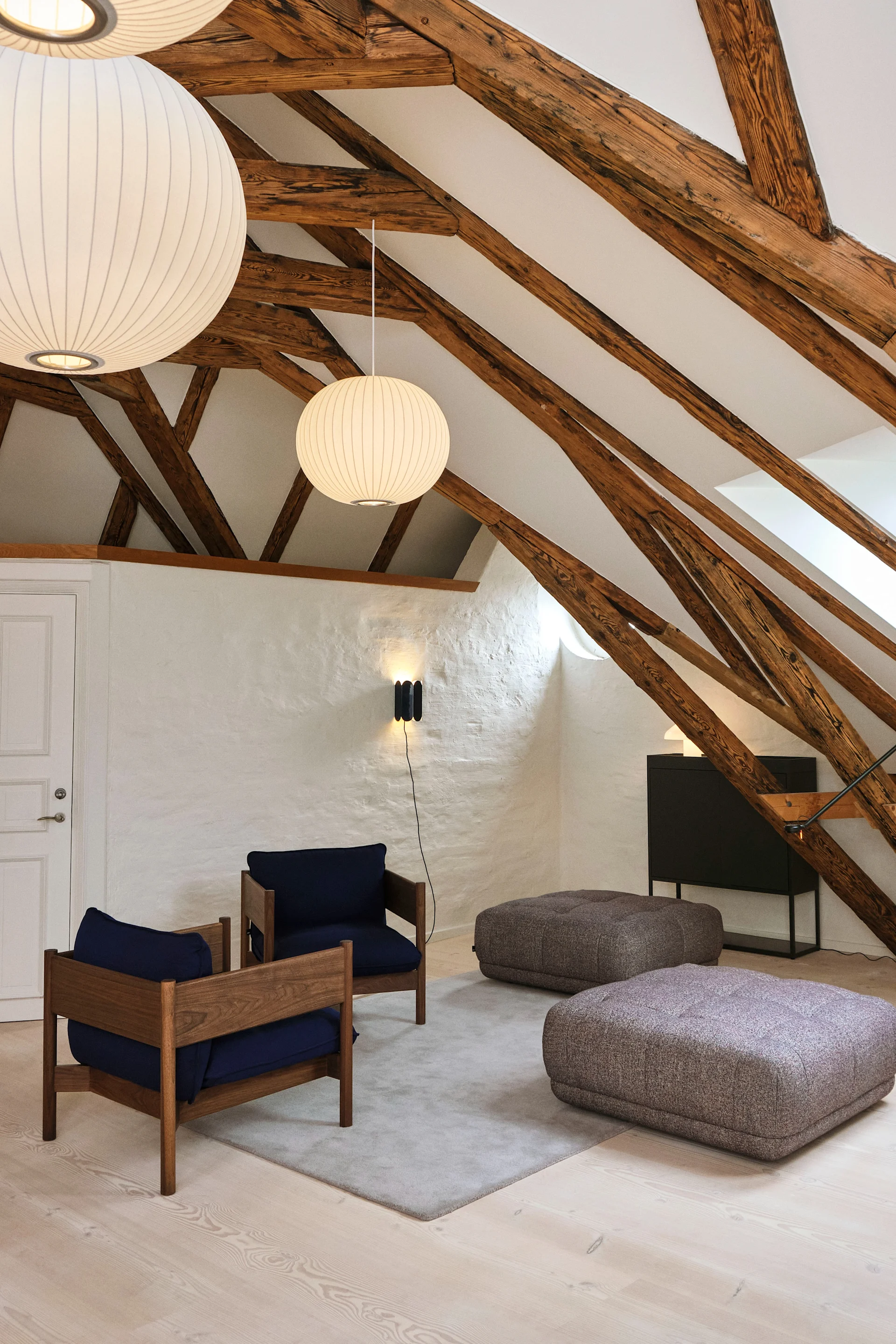 Lámparas de techo para el salón: en un salón con techos altos y vigas de madera cuelgan varias lámparas colgantes Nelson Bubble Ball de Hay.