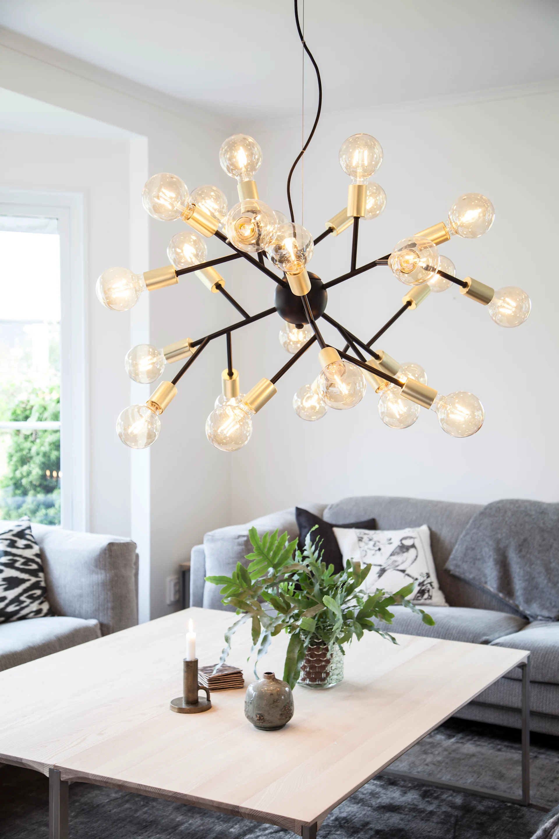 Sobre una mesa de centro, cuelga la extraordinaria lámpara de techo Heroes de By Rydéns.